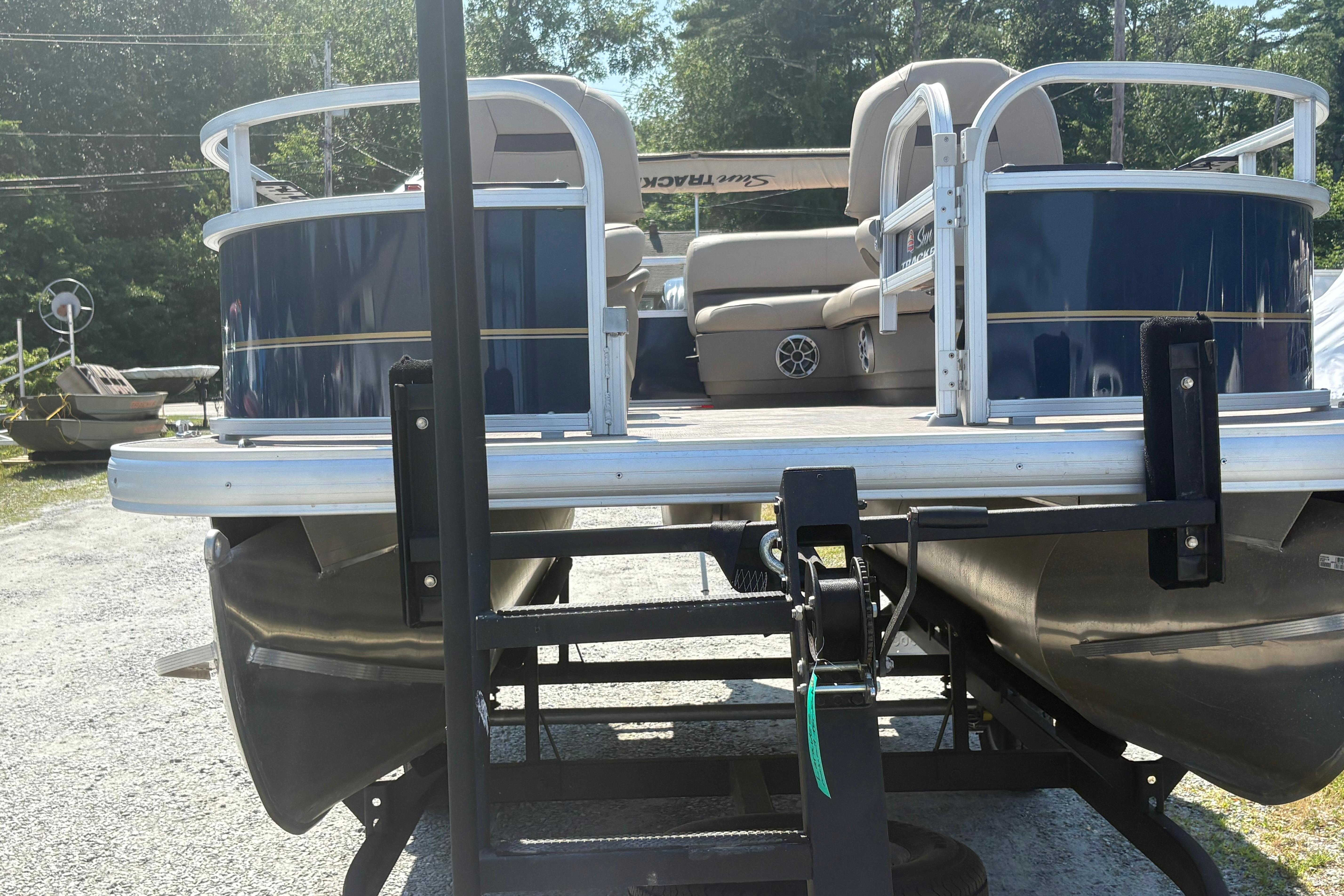 2024 Sun Tracker Bass Buggy 16 DLX pontoon boat on trailer, parked outdoors.