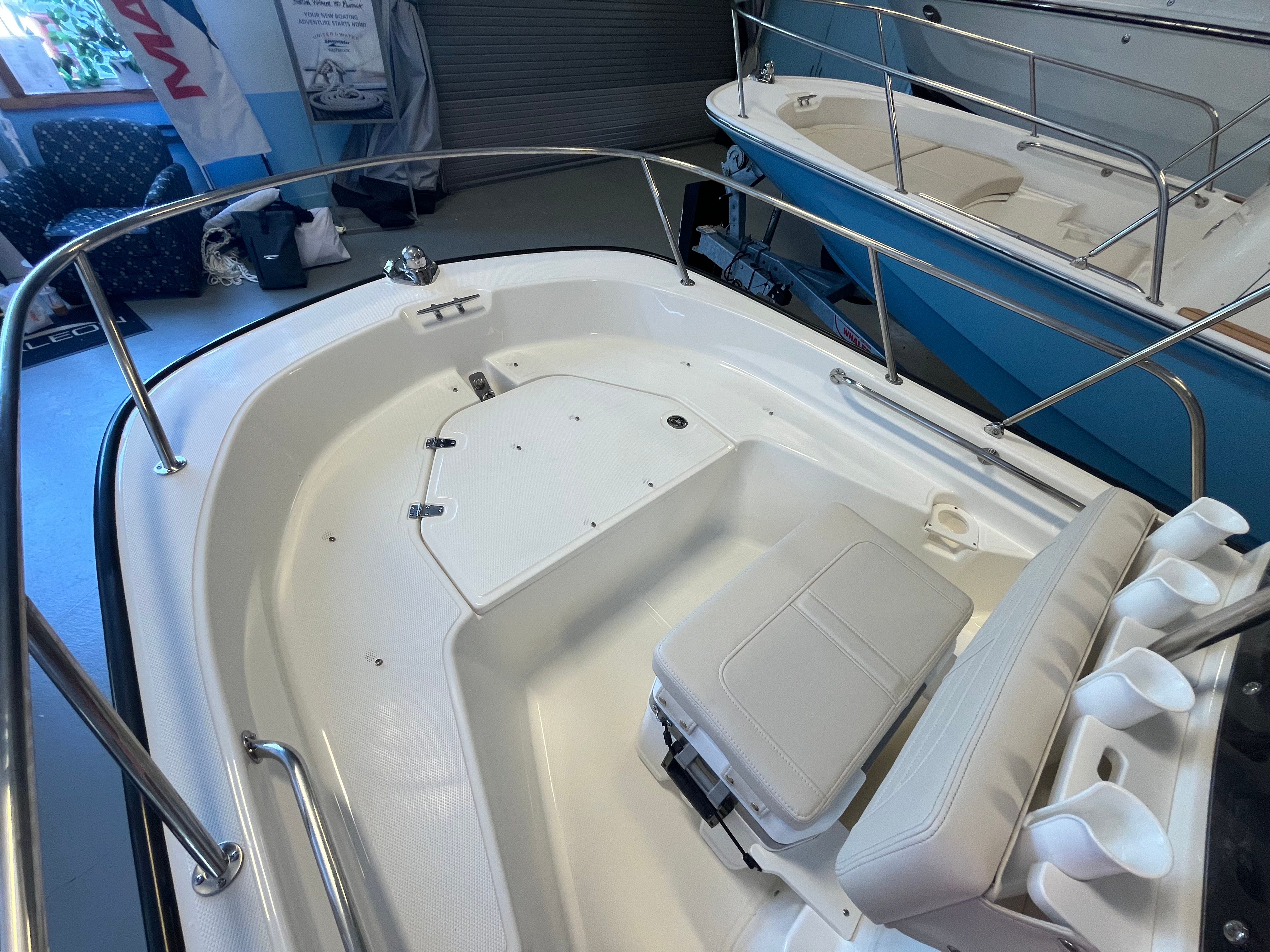 The image shows the cockpit of a Boston Whaler 150 Montauk with white seating and stainless steel railing.