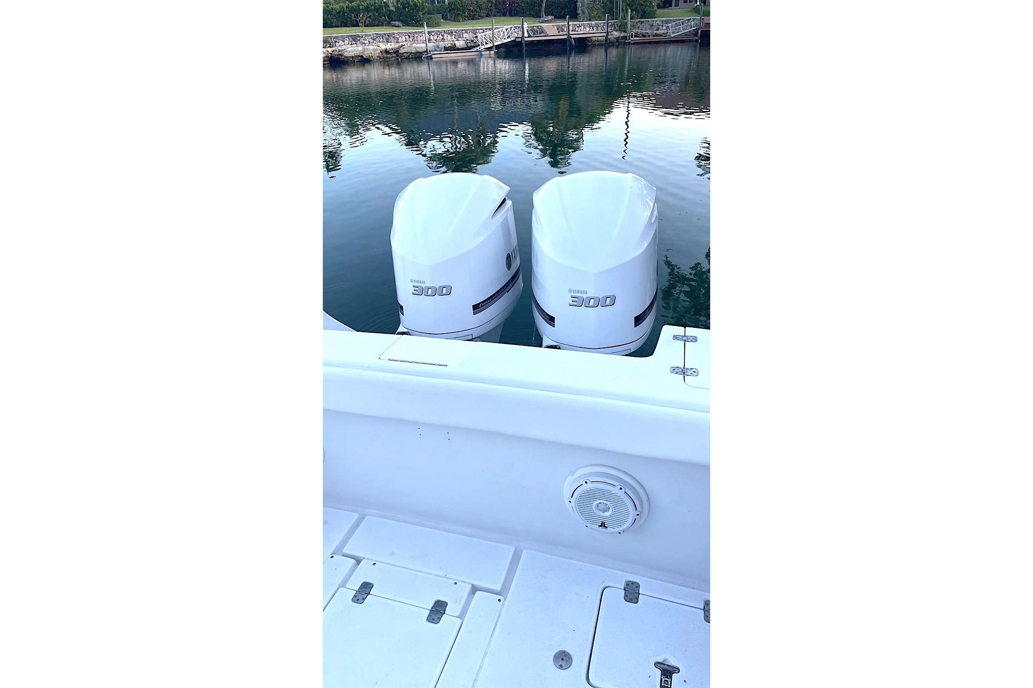 Twin Yamaha 300 engines on a 2002 Intrepid 323 Cuddy boat, docked by calm waters.