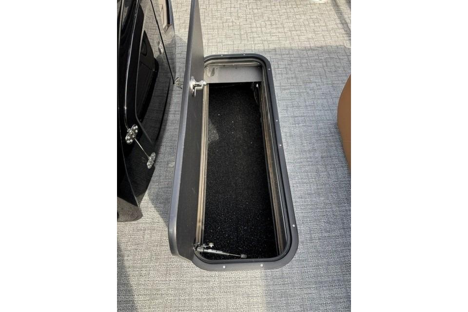 Open storage compartment on 2026 Regency 230 DL boat with carpeted interior.