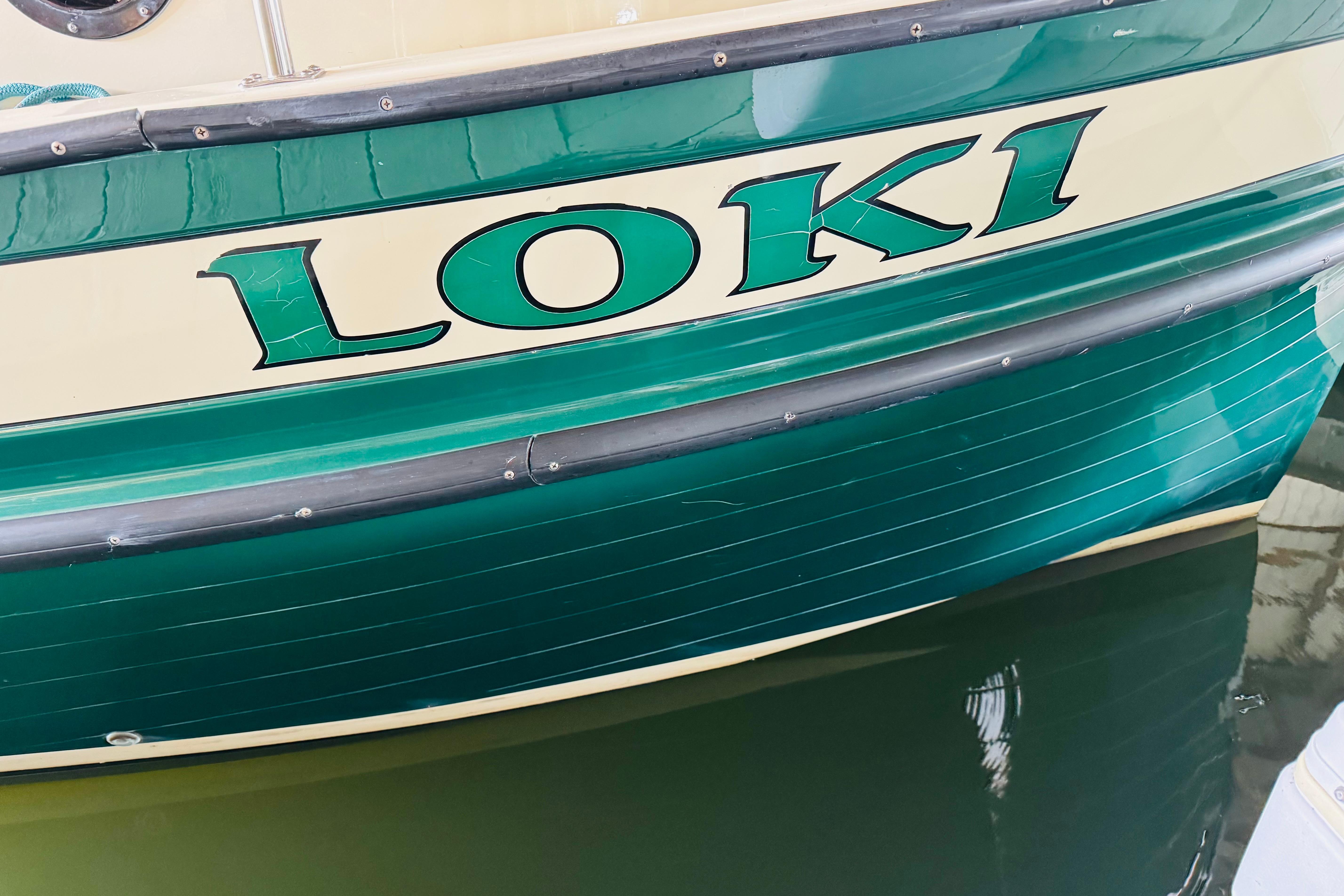 Green and cream Nordic Tug 32 boat named "Loki," 1996 model, docked in water.