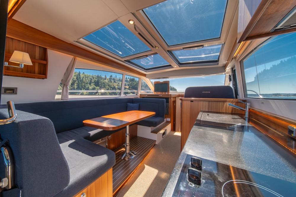Luxurious interior of 2022 Nimbus 405 Coupé yacht with panoramic windows and modern furnishings.
