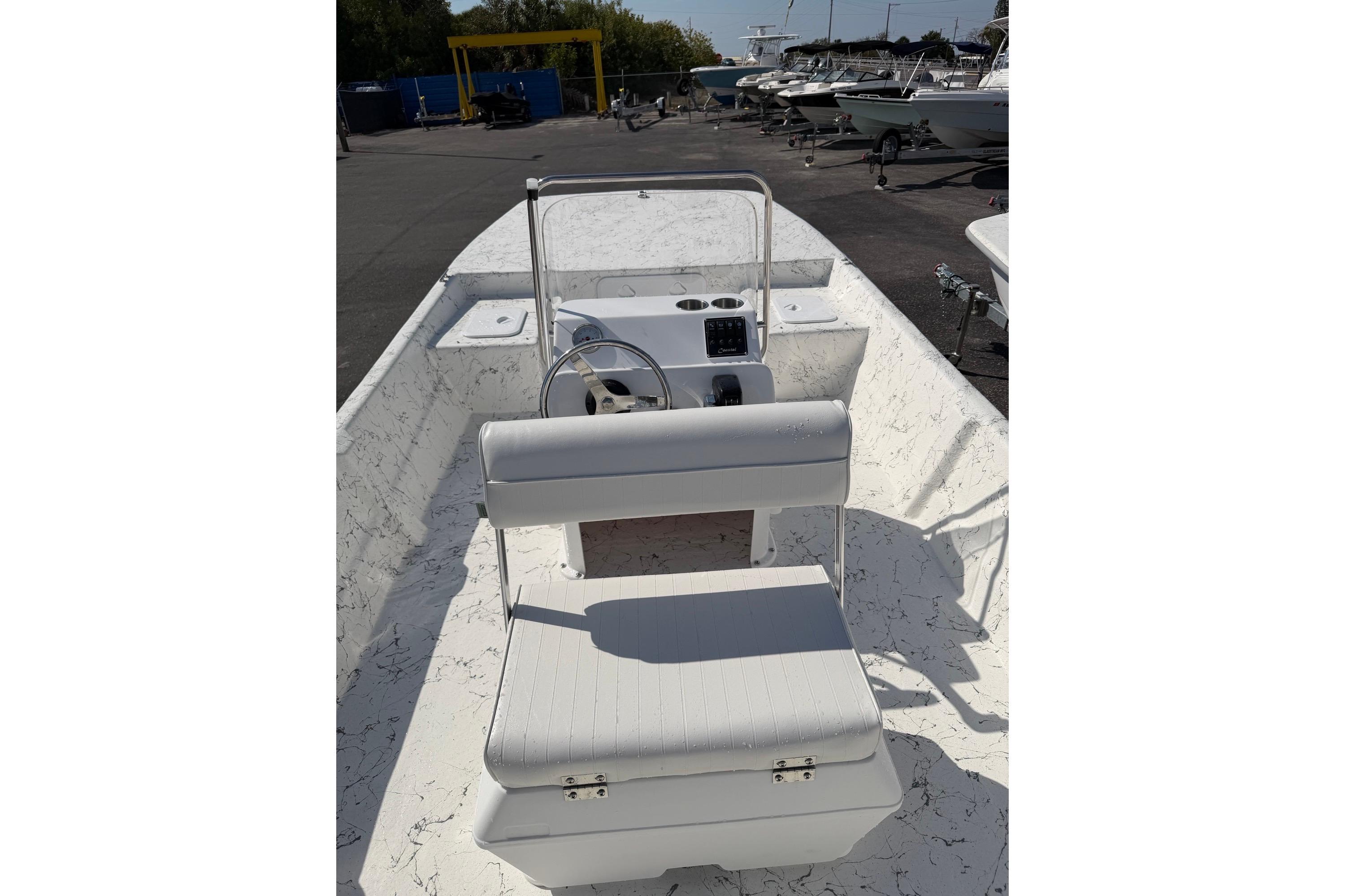2027 Coastal Skiff 184 boat interior with steering console and seating in a marina setting.