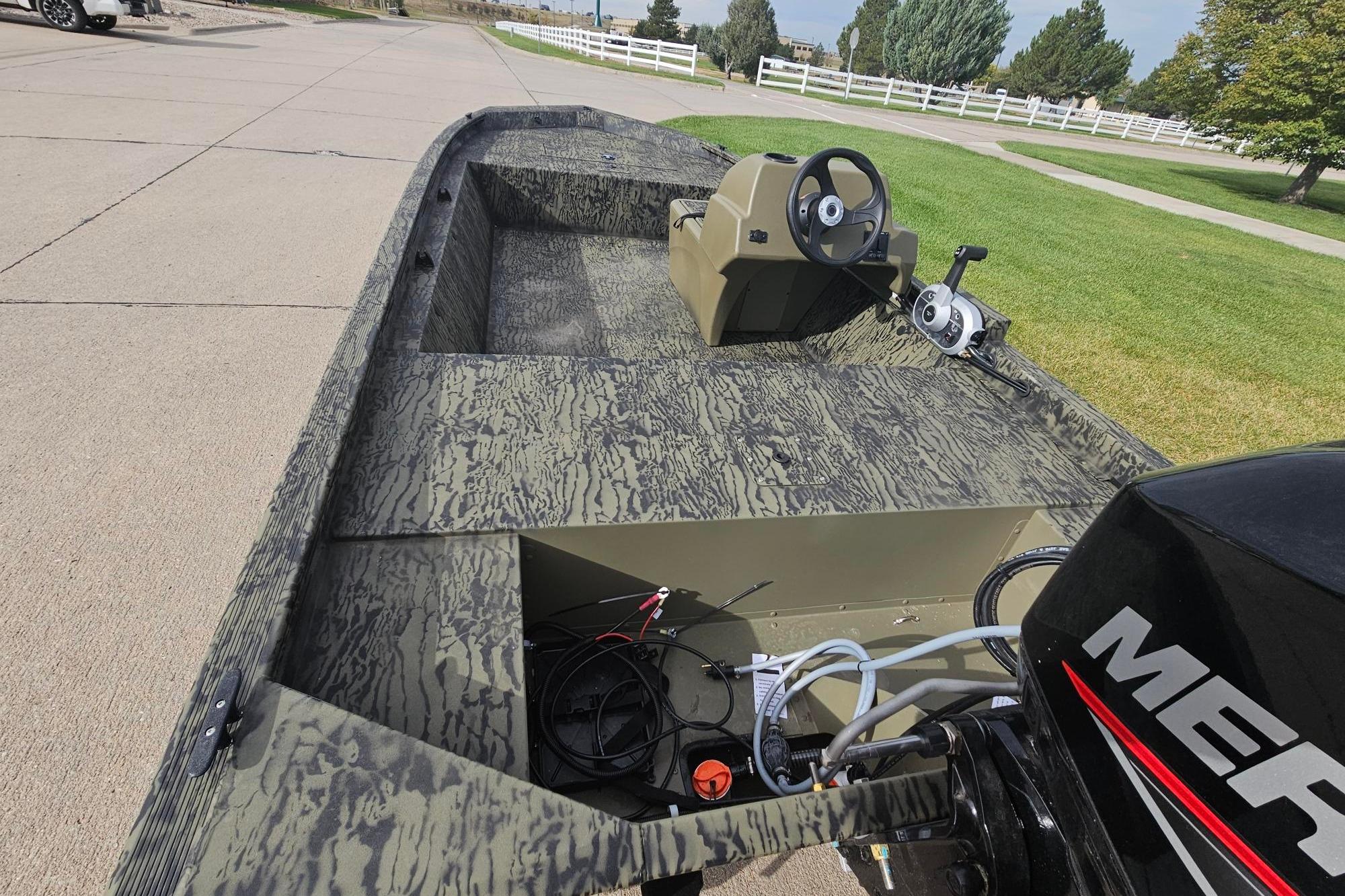 2026 Tracker Grizzly 1648 SC boat with camo design and Mercury engine, parked on pavement.