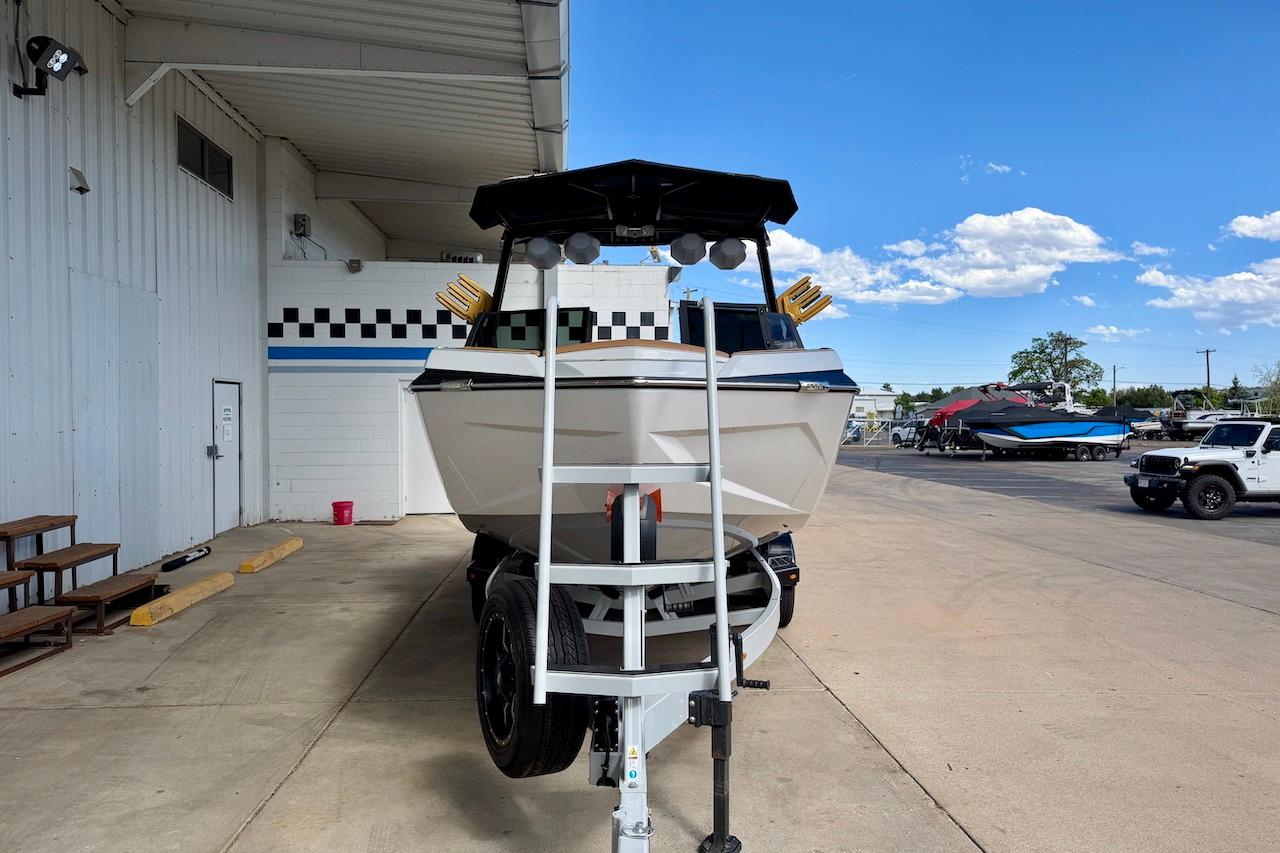 2025 Tigé Ultré 25ZX boat on trailer, parked outside a building under a clear blue sky.