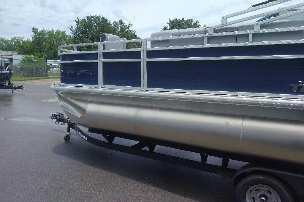 2026 Sun Tracker SportFish 20 DLX pontoon boat on trailer, parked outdoors.