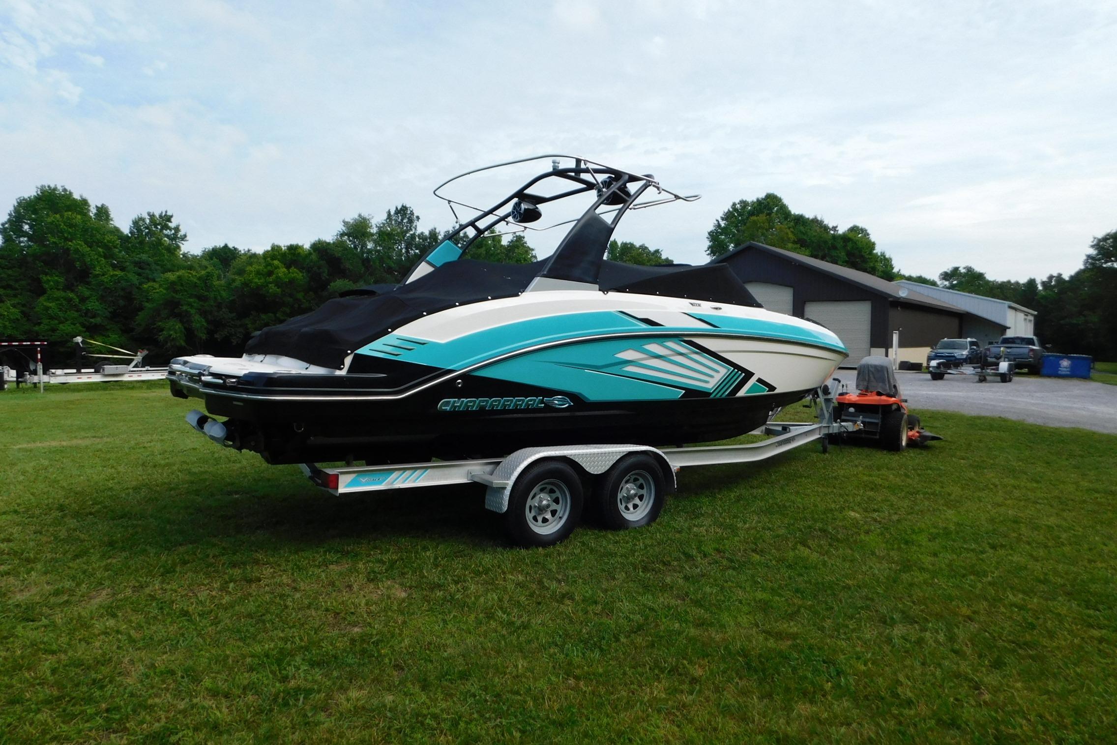2016 CHAPPARRAL 243 boat on trailer, parked on grass near a building.