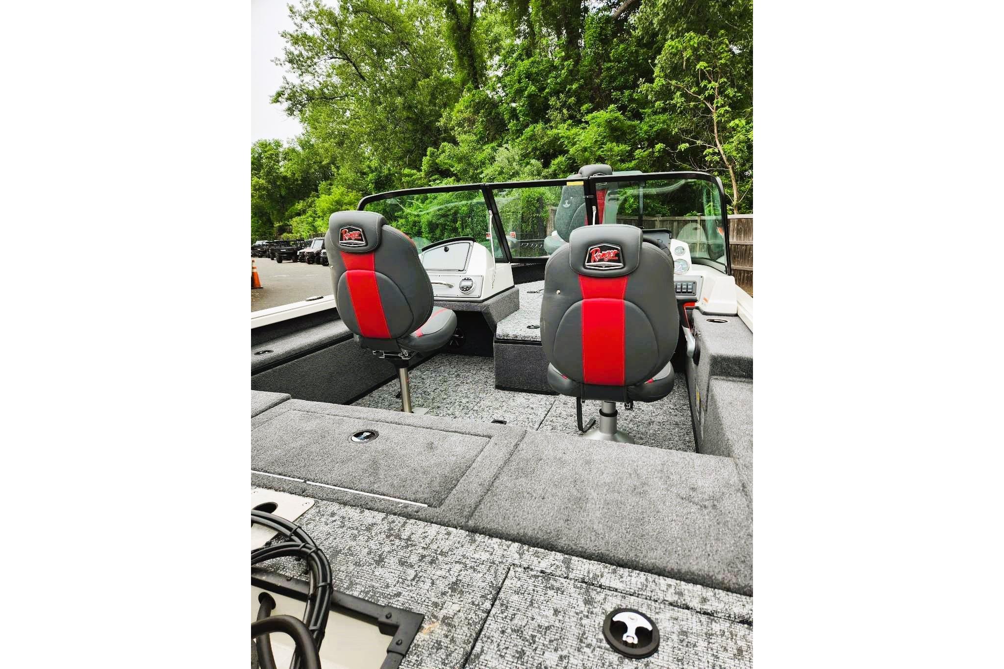 2026 Ranger VS1682SC Reata boat interior with dual seats and dashboard, surrounded by lush greenery.