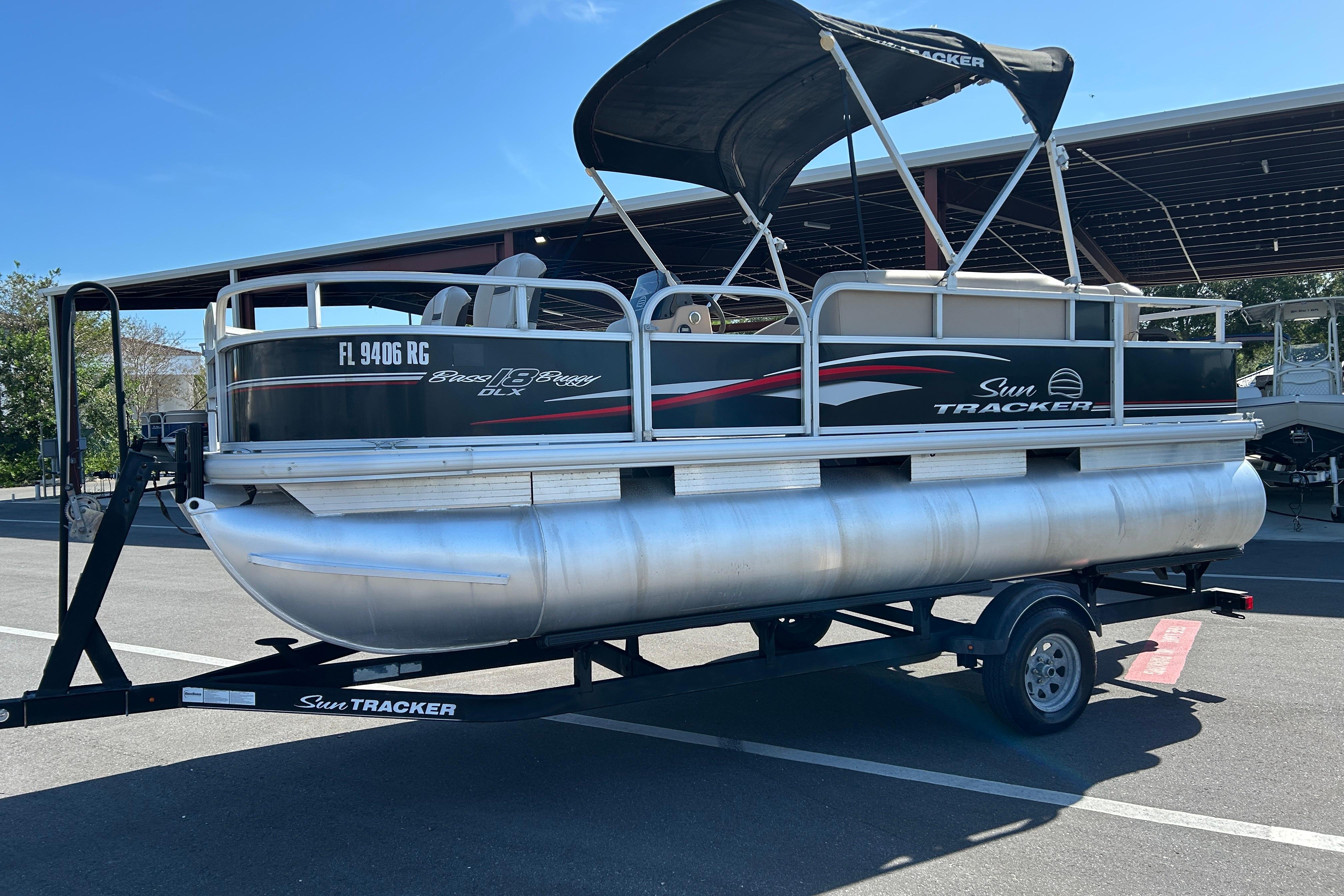 2017 Sun Tracker Bass Buggy 18 DLX pontoon boat on trailer in parking lot.