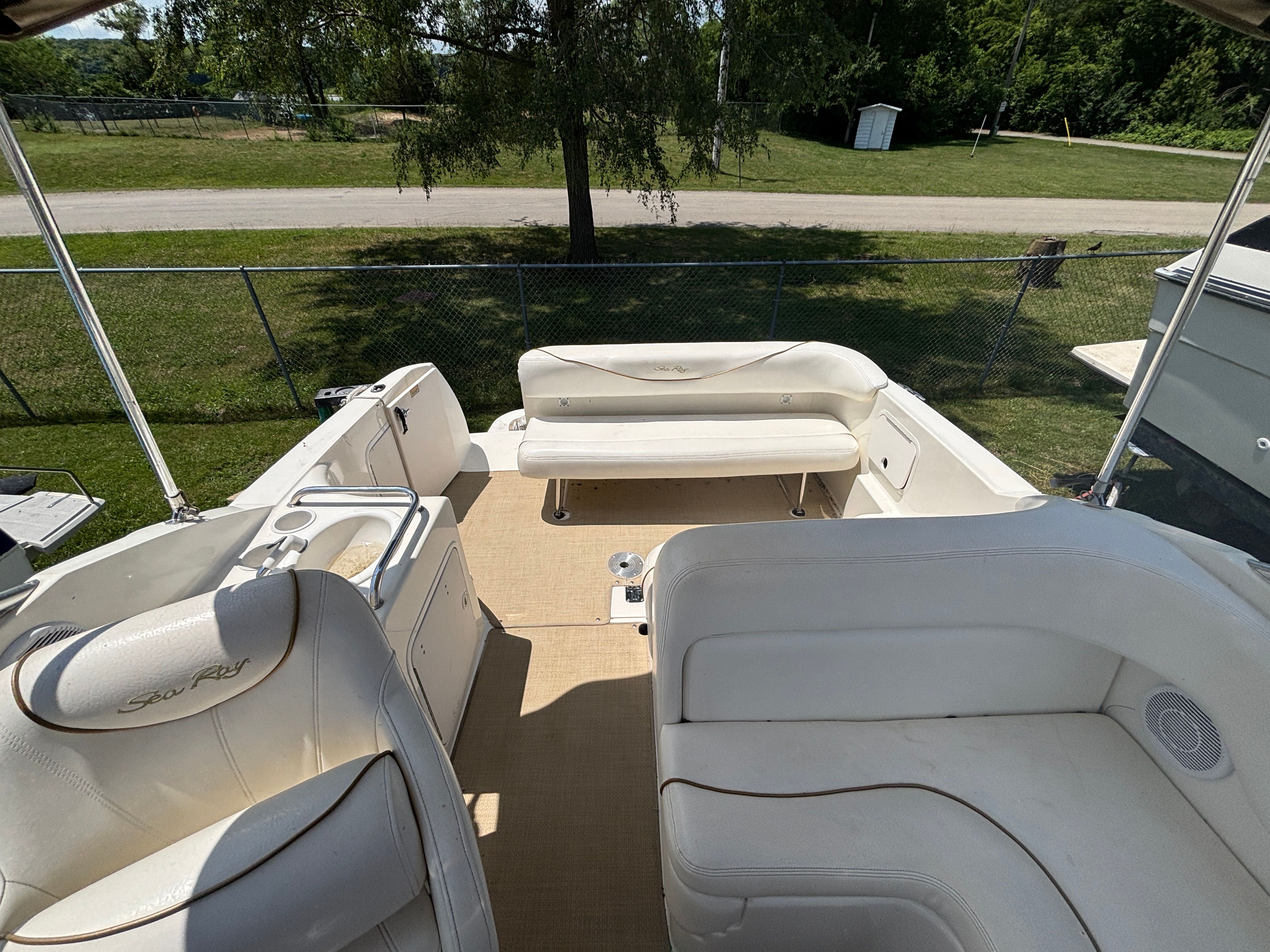 The image shows the cockpit of a Sea Ray Sundancer 260 with white seating and a table.