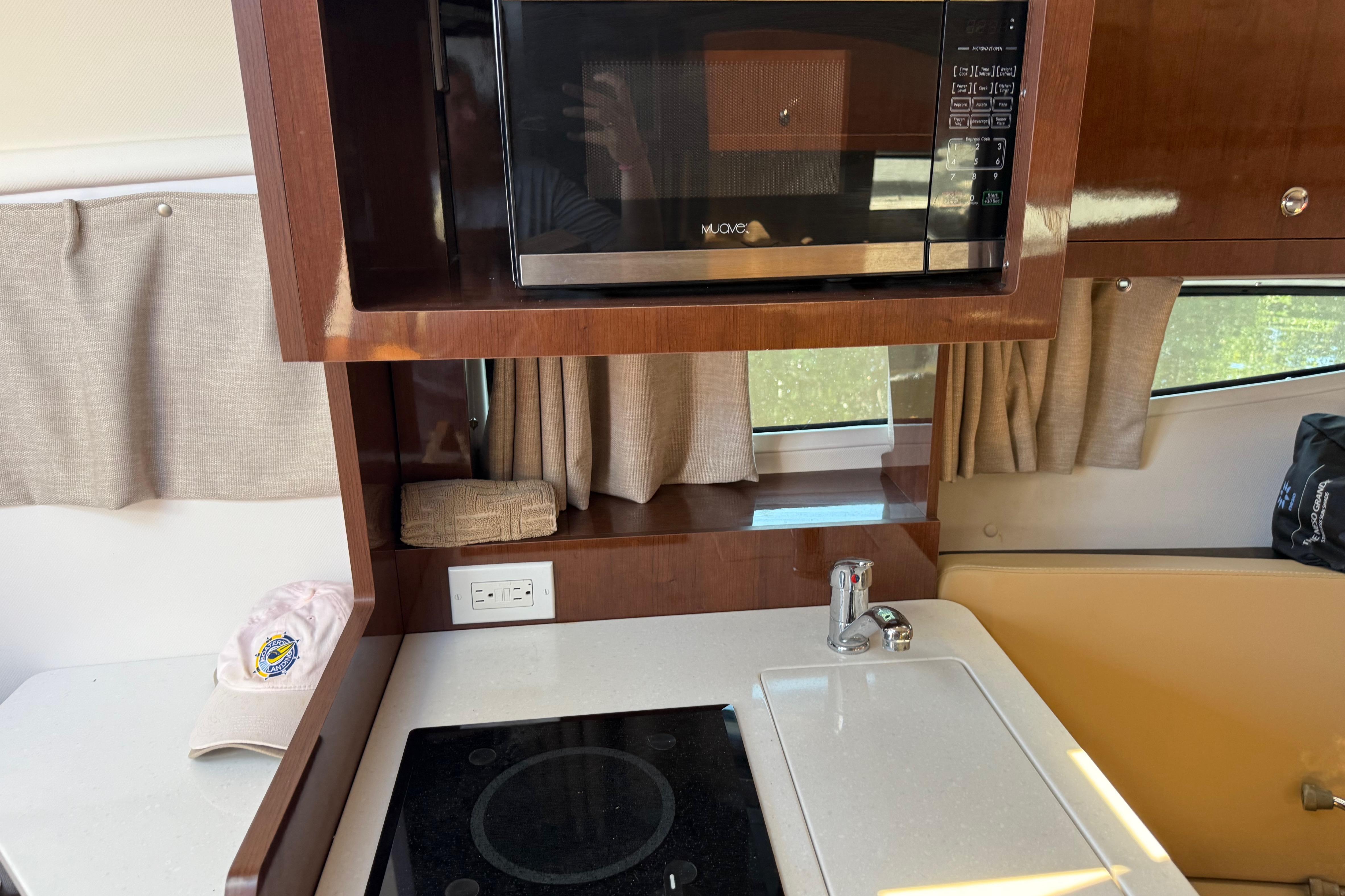 2017 Four Winns V275 boat interior with microwave, stove, and sink in the kitchen area.