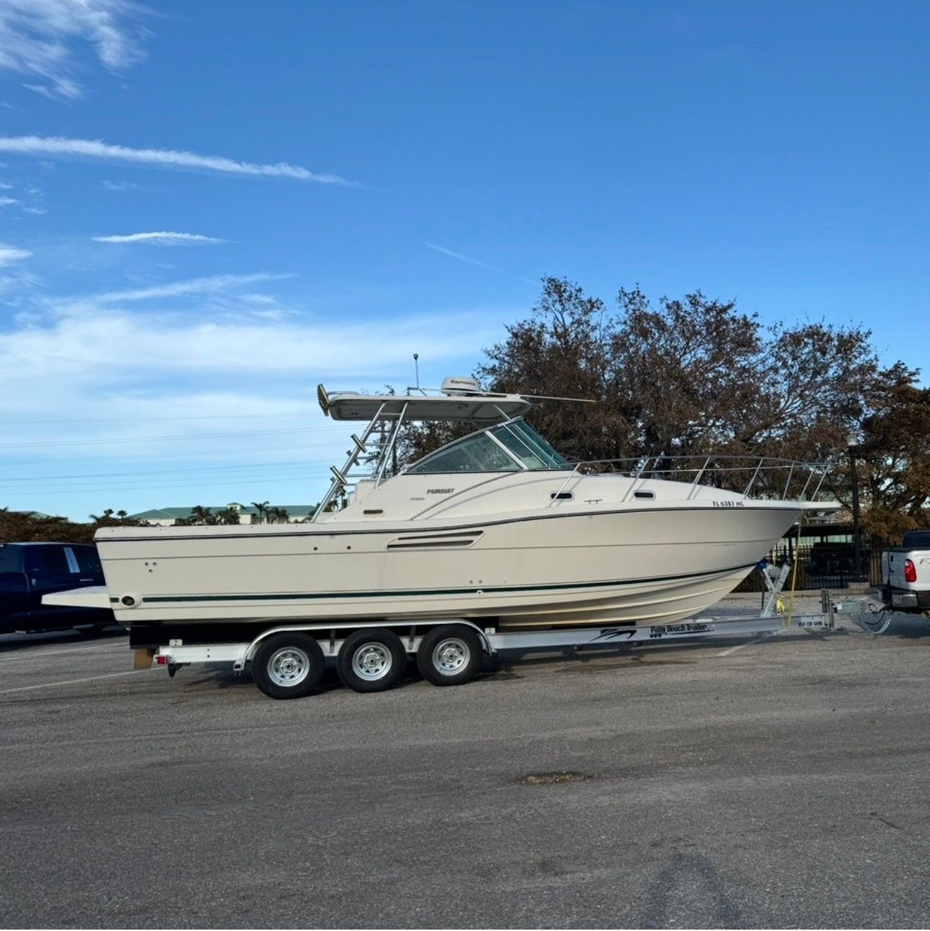A 2002 Pursuit 3000 Express boat on a trailer in a parking lot.