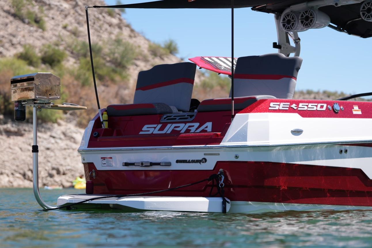 2023 Supra SE 550 boat with grill, on water, scenic background.