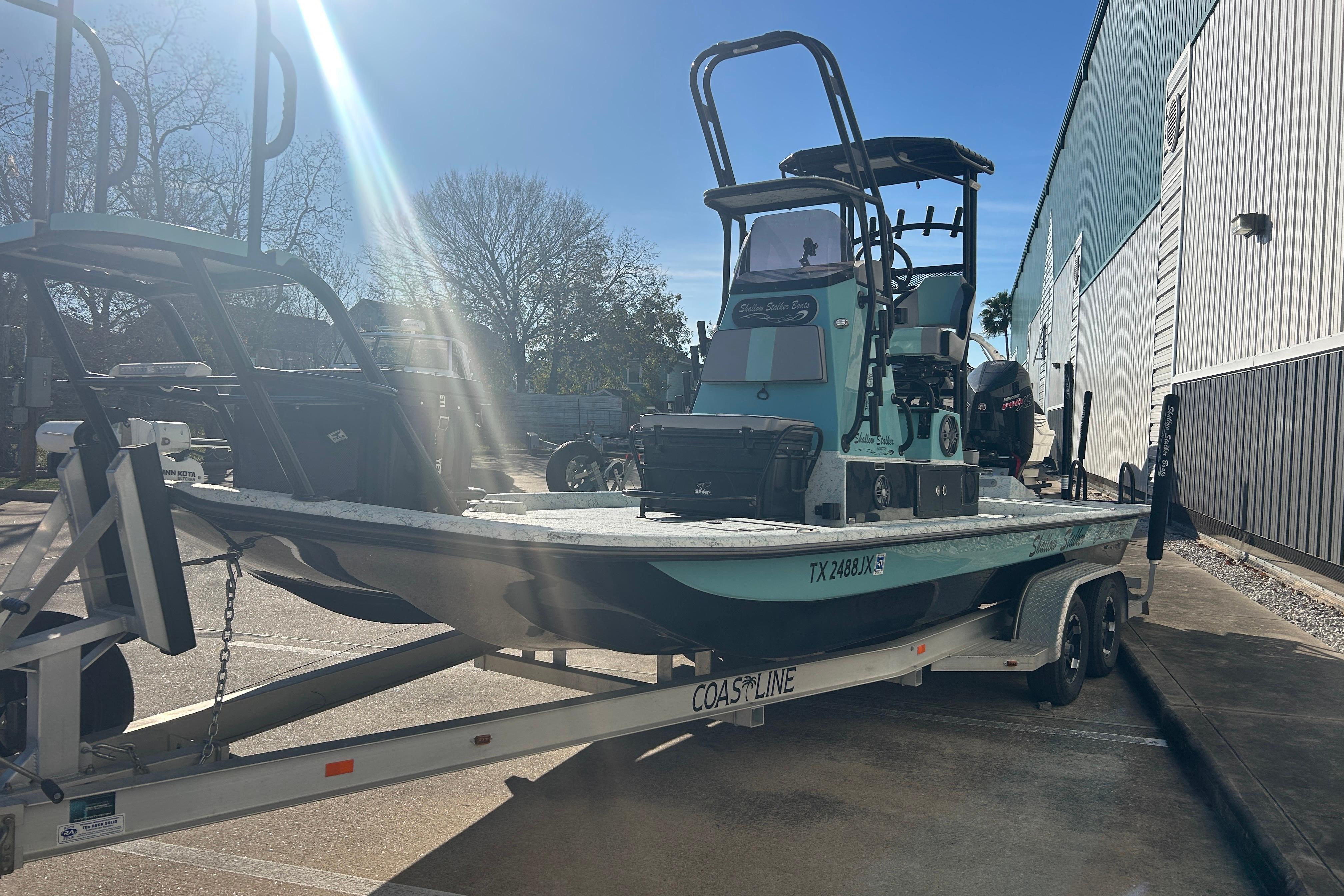 2021 Shallow Stalker Cat 240 Pro Elite boat on trailer in sunny parking lot.