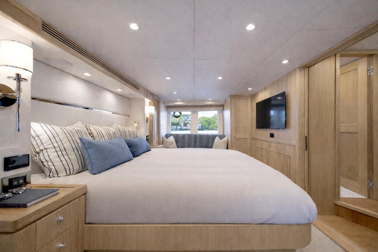 Luxurious bedroom interior of 2027 Offshore Yachts 70 CE, featuring elegant wood finishes and modern amenities.
