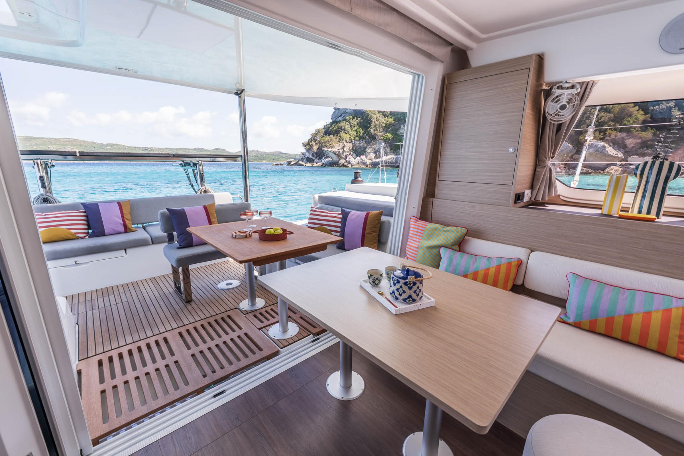 Luxurious Lagoon 38 catamaran interior with colorful cushions, overlooking serene turquoise waters.