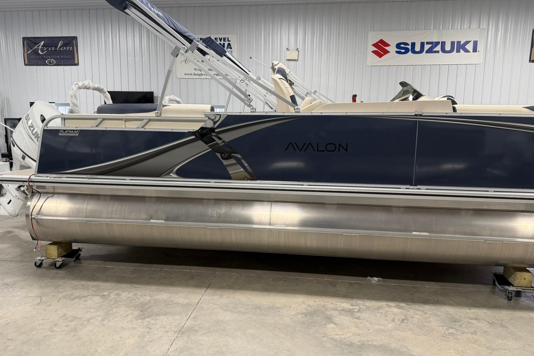 2026 Avalon LSZ Elite 21' pontoon boat in showroom with Suzuki engine.
