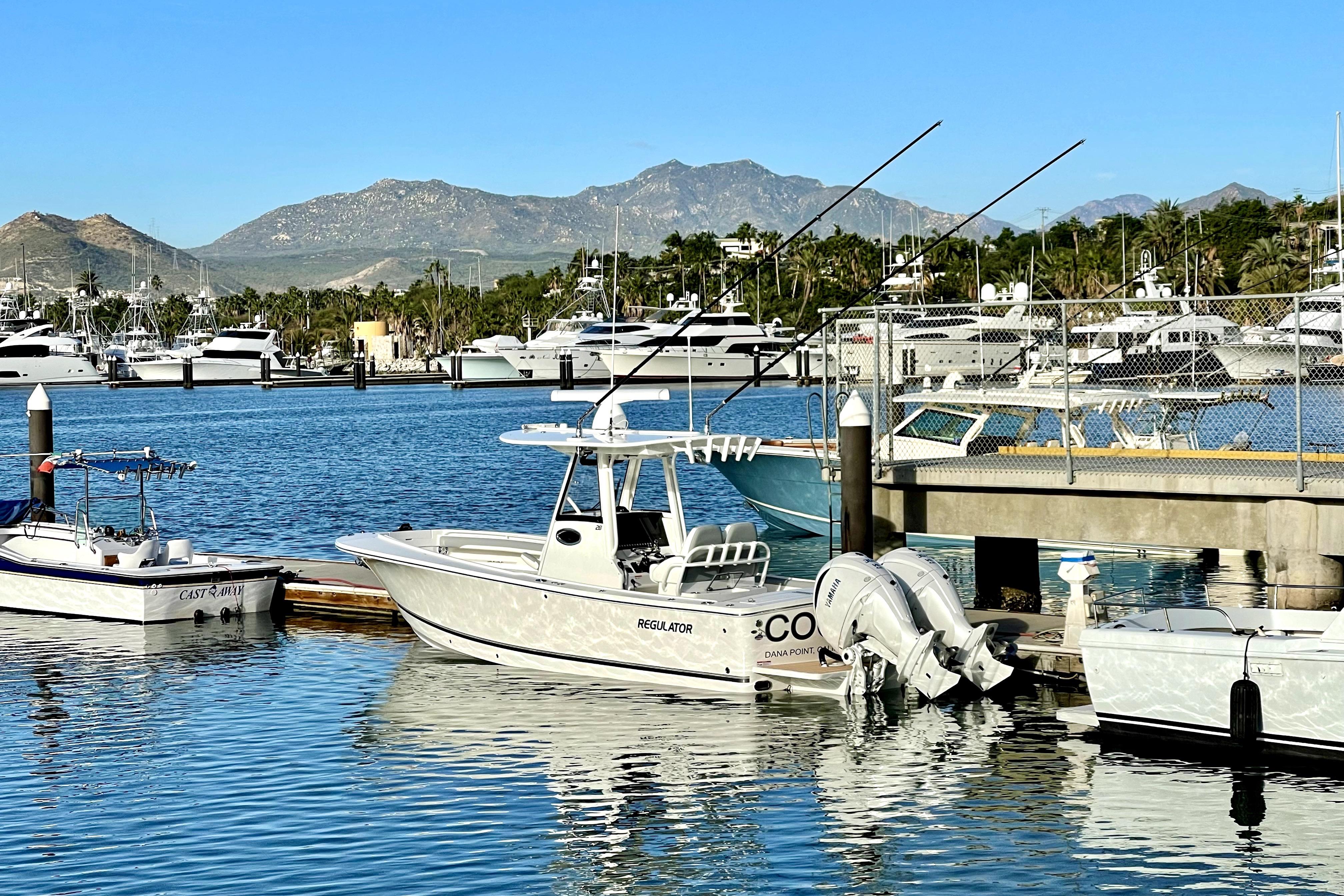 2022 Regulator 28 boat docked in a marina with scenic mountain backdrop.