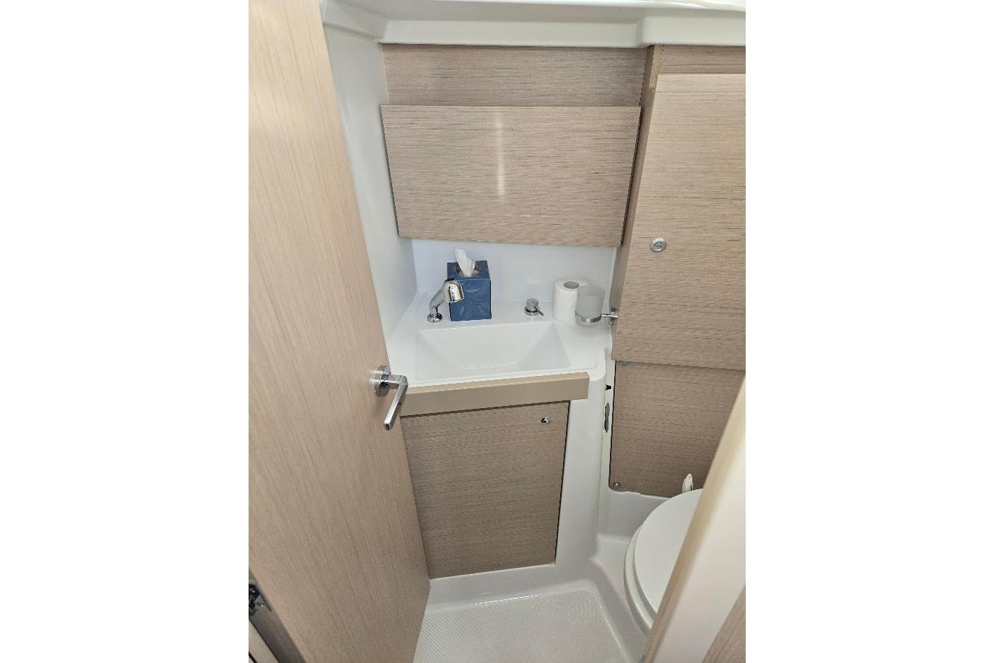 Compact bathroom in 2023 Beneteau Oceanis 38.1 yacht with sink and toilet.