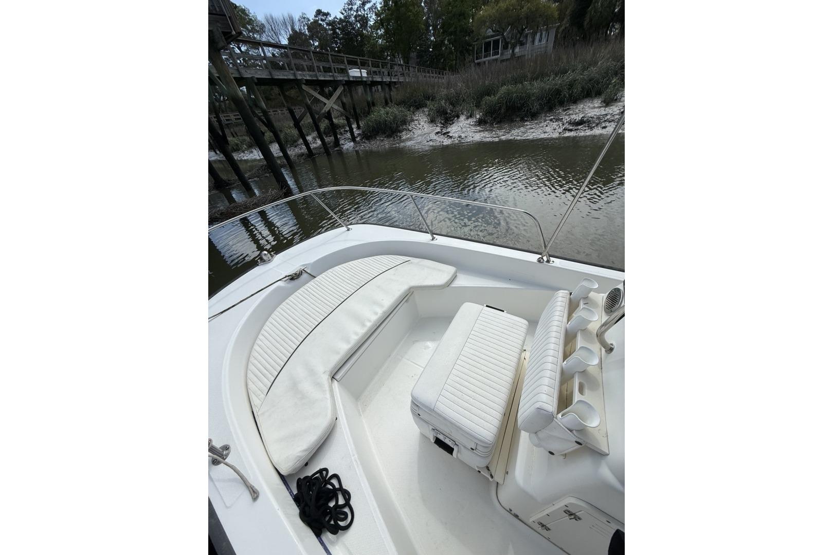 2016 Boston Whaler 170 Montauk boat interior with seating and rod holders by a dock.