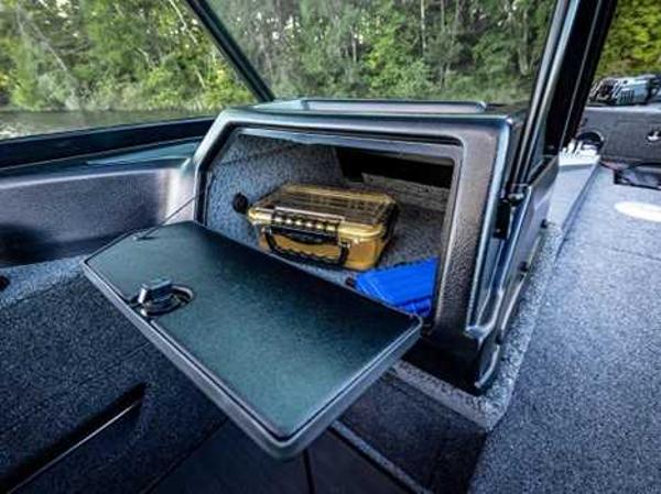 2026 Lund 2075 IMPACT XS boat storage compartment with gear and forest backdrop.
