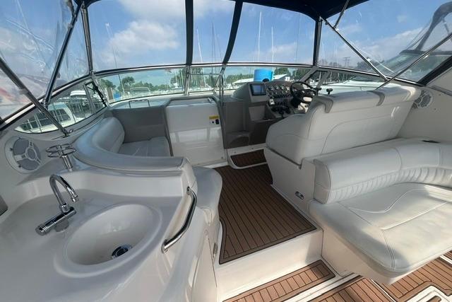 2004 Cruisers Yachts 3372 Express interior with helm, seating, and sink, featuring wood flooring.