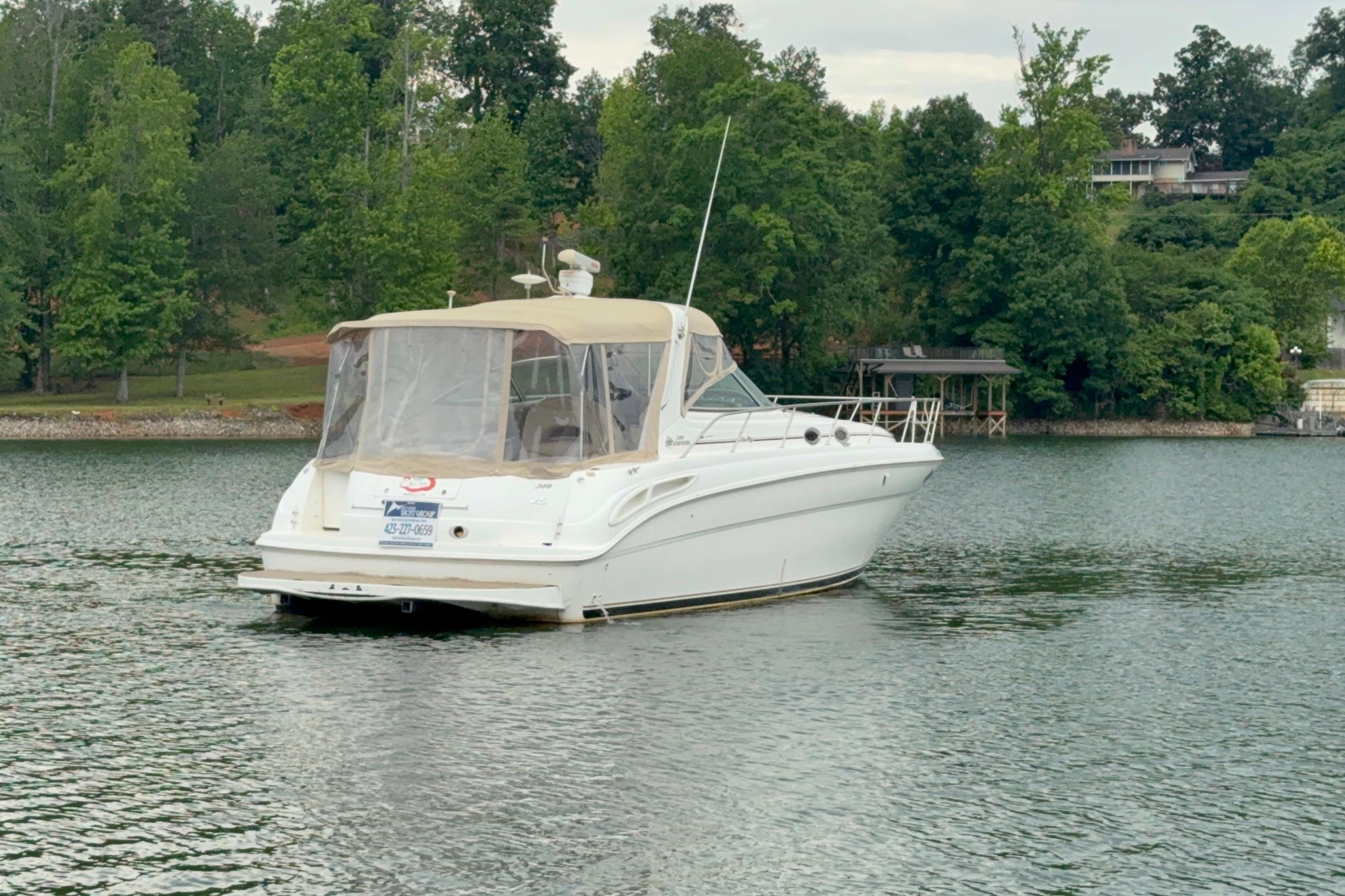 2001 Sea Ray 380 Sundancer yacht on a serene lake with lush green surroundings.
