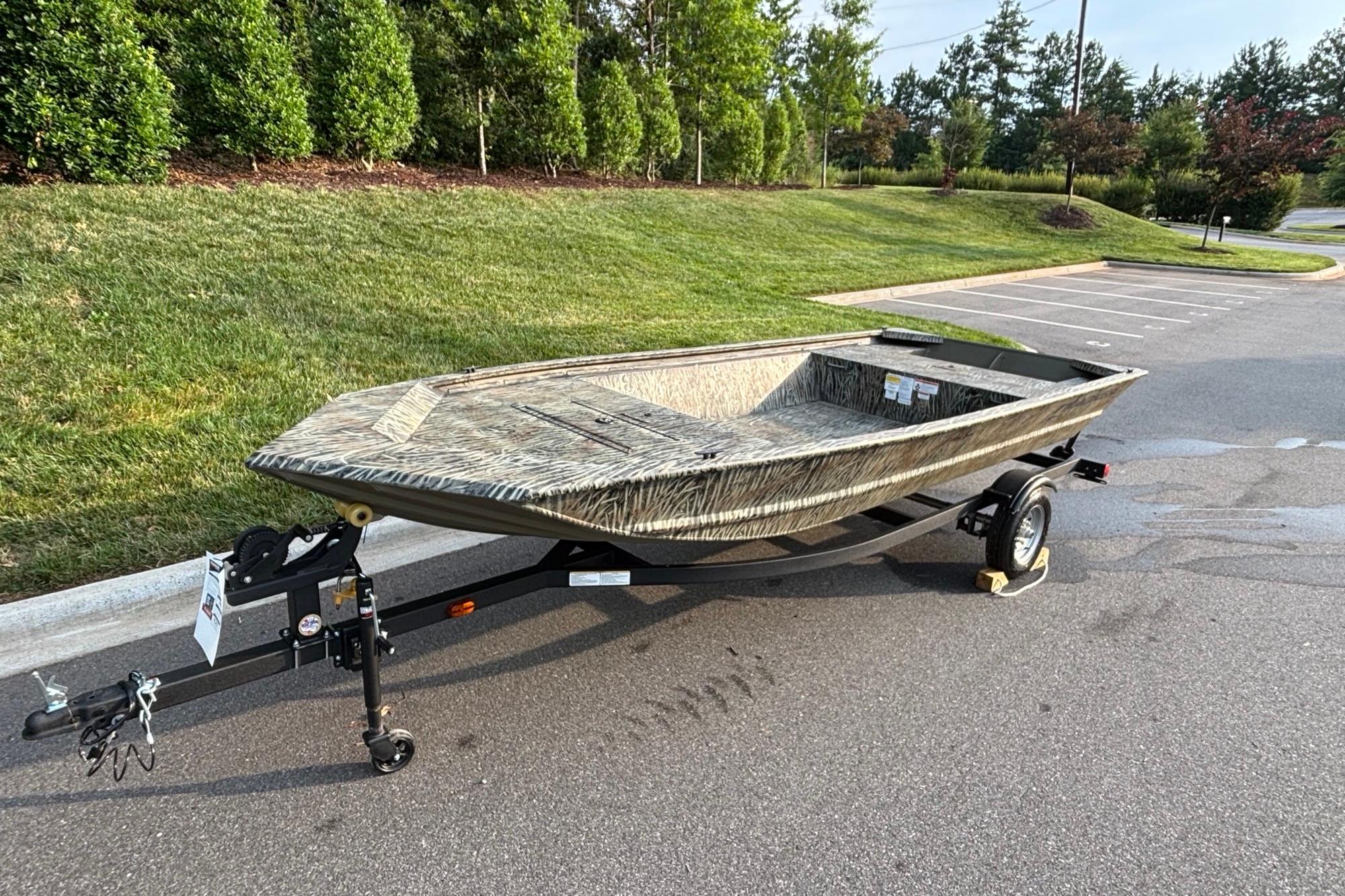 2026 Tracker Grizzly 1648 Utility boat on trailer in parking lot.