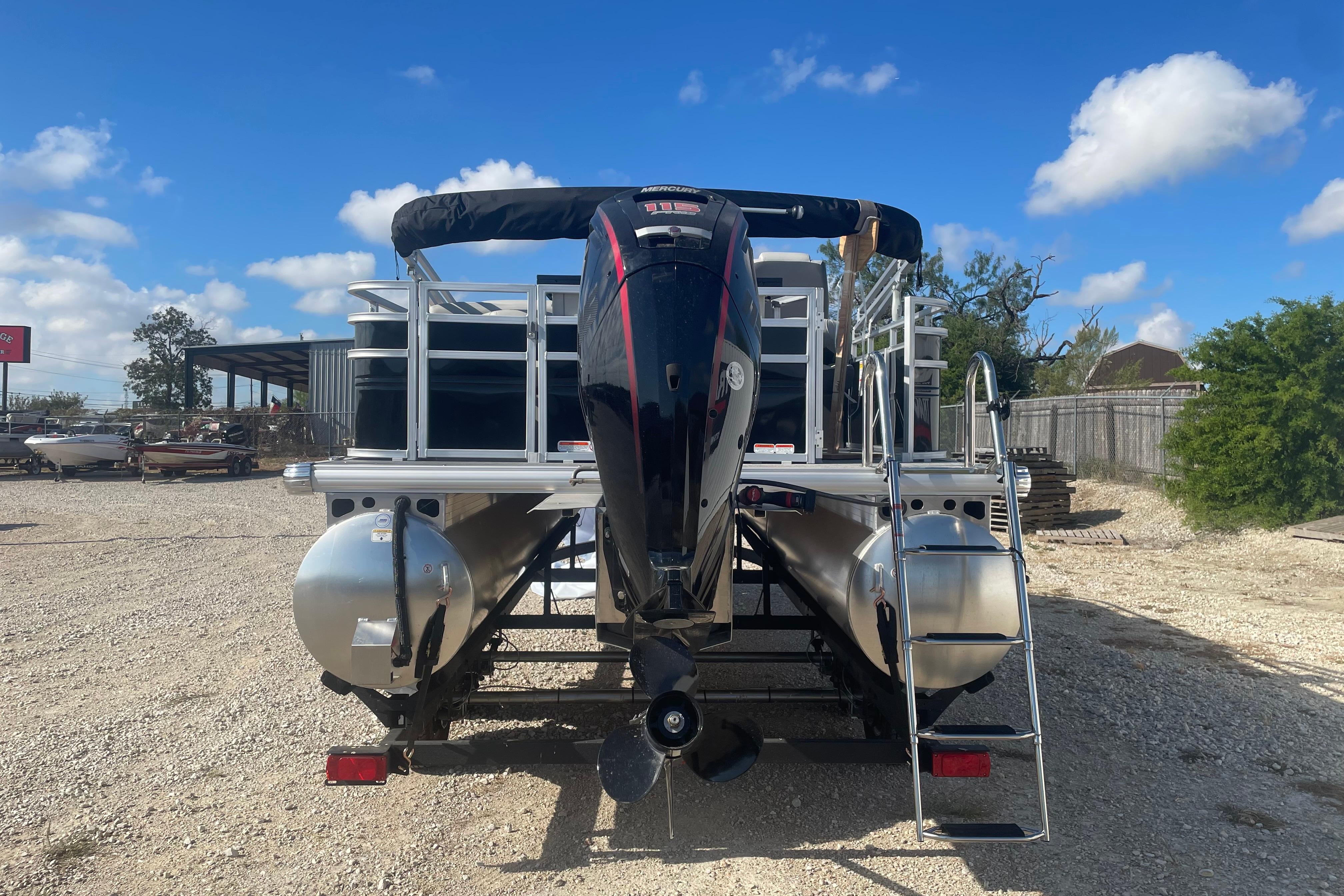 2026 Sun Tracker Fishin' Barge 20 DLX pontoon boat with outboard motor, parked outdoors.