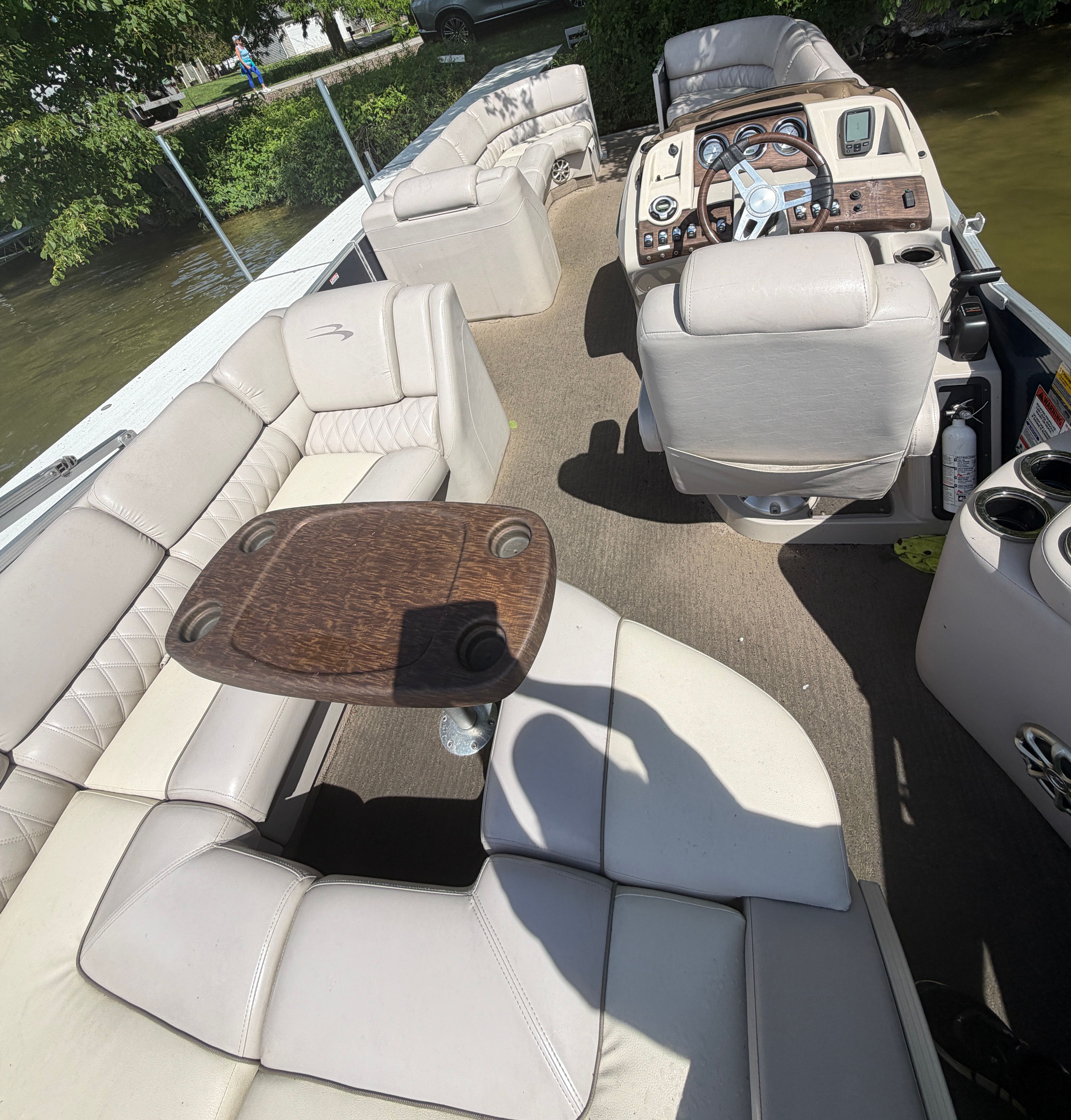 Interior of a Bennington 2350 RCL pontoon boat with beige seating and a wooden table.