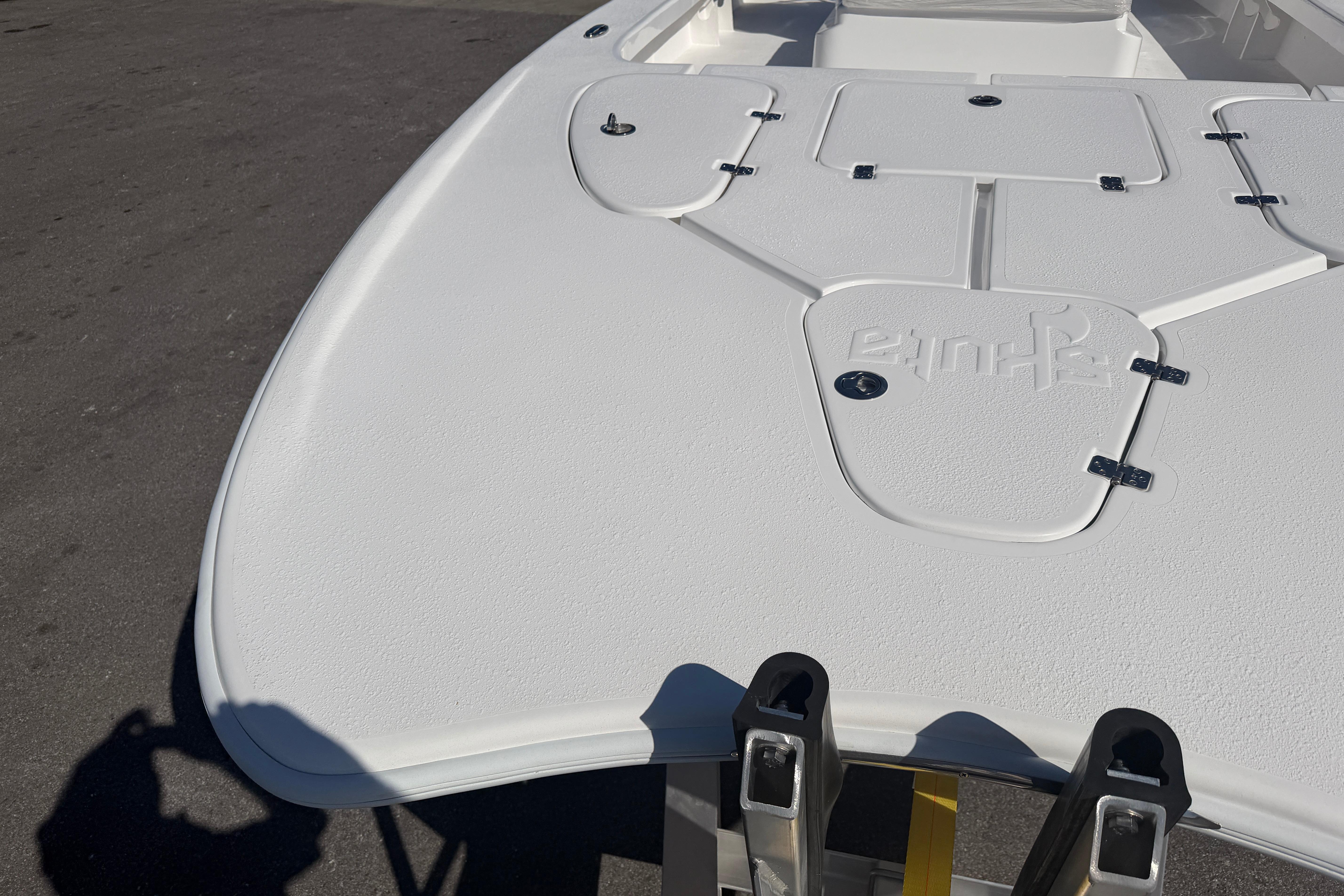 2026 Skuta 24 Cat boat deck with storage compartments and textured surface.