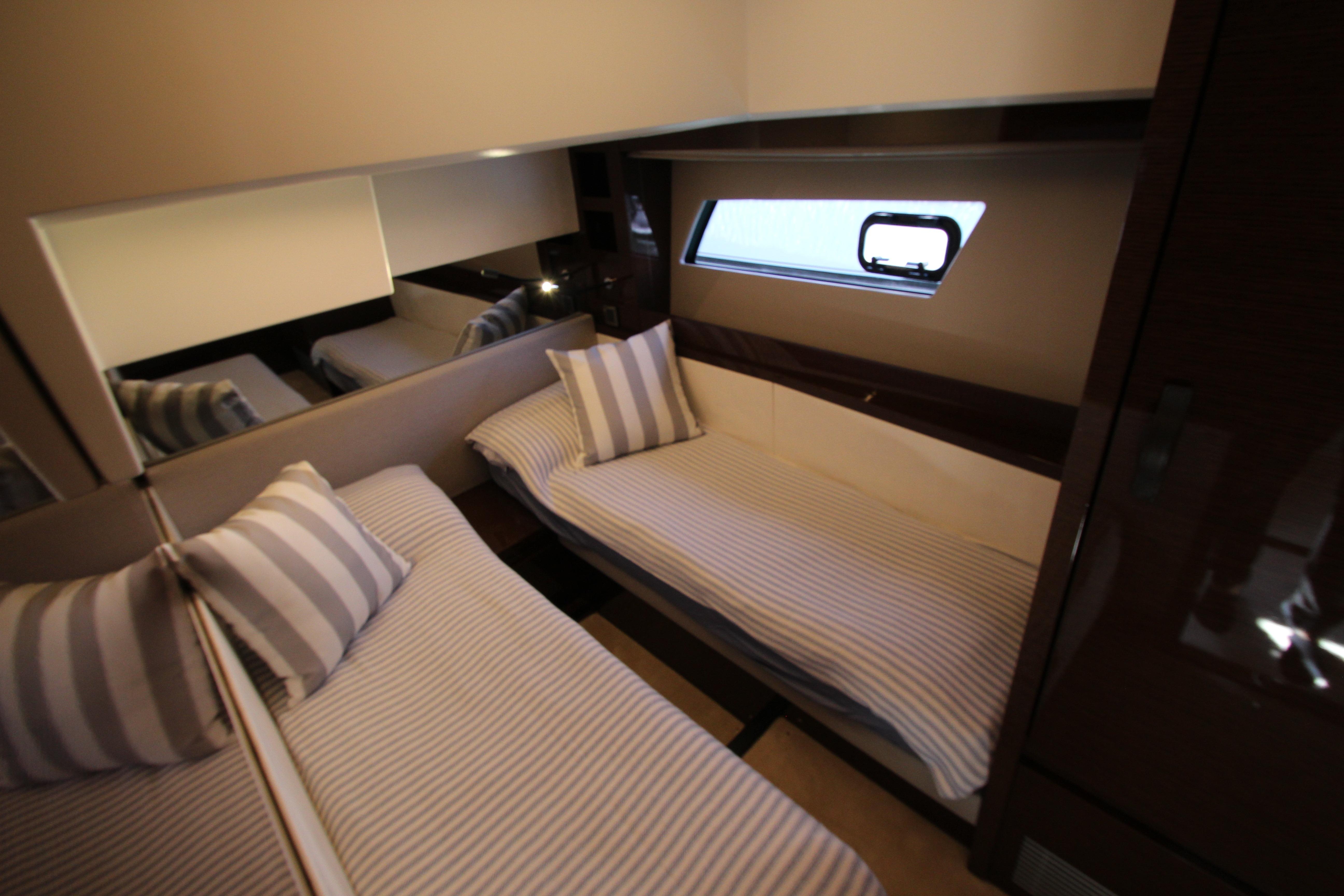 Luxurious twin cabin interior of 2022 Prestige 520 yacht with striped bedding.