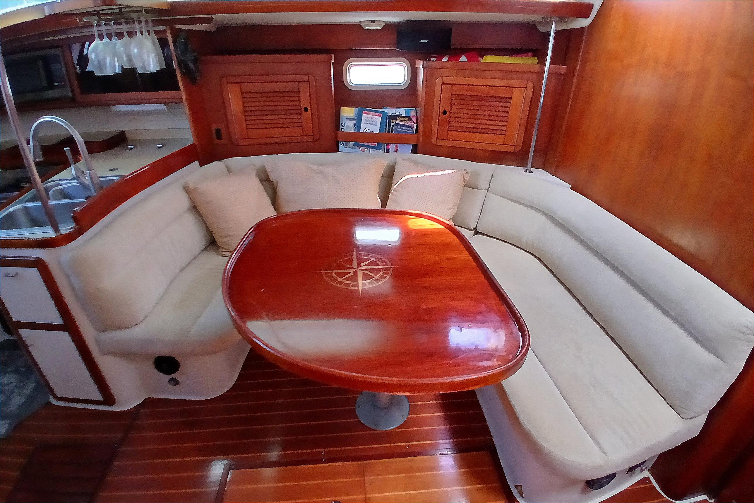 Interior of a 1995 Catalina 42 MkII sailboat with cozy seating and wooden table.
