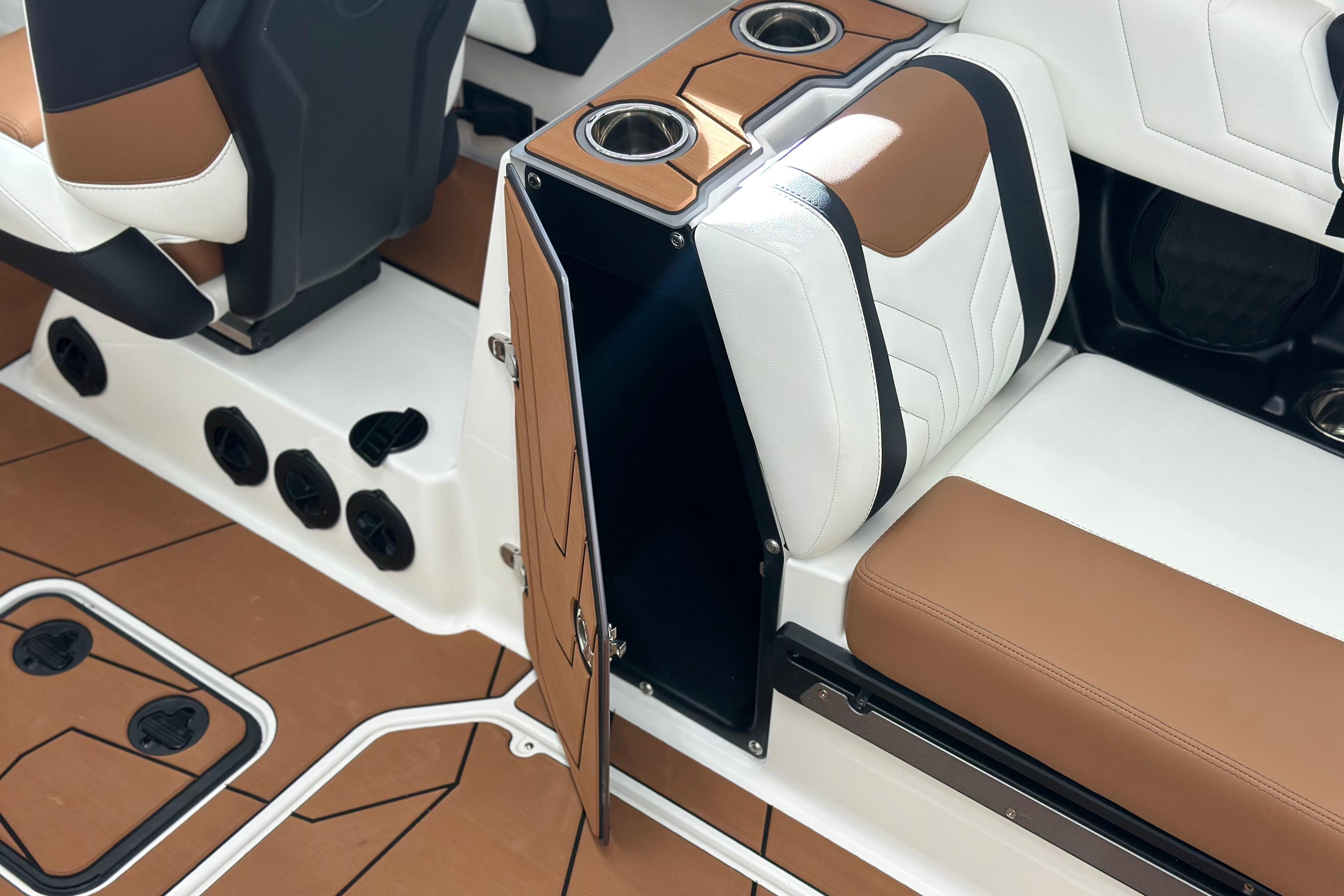 2026 Malibu Wakesetter 25 LSV interior with brown and white seating, cup holders, and storage compartment.