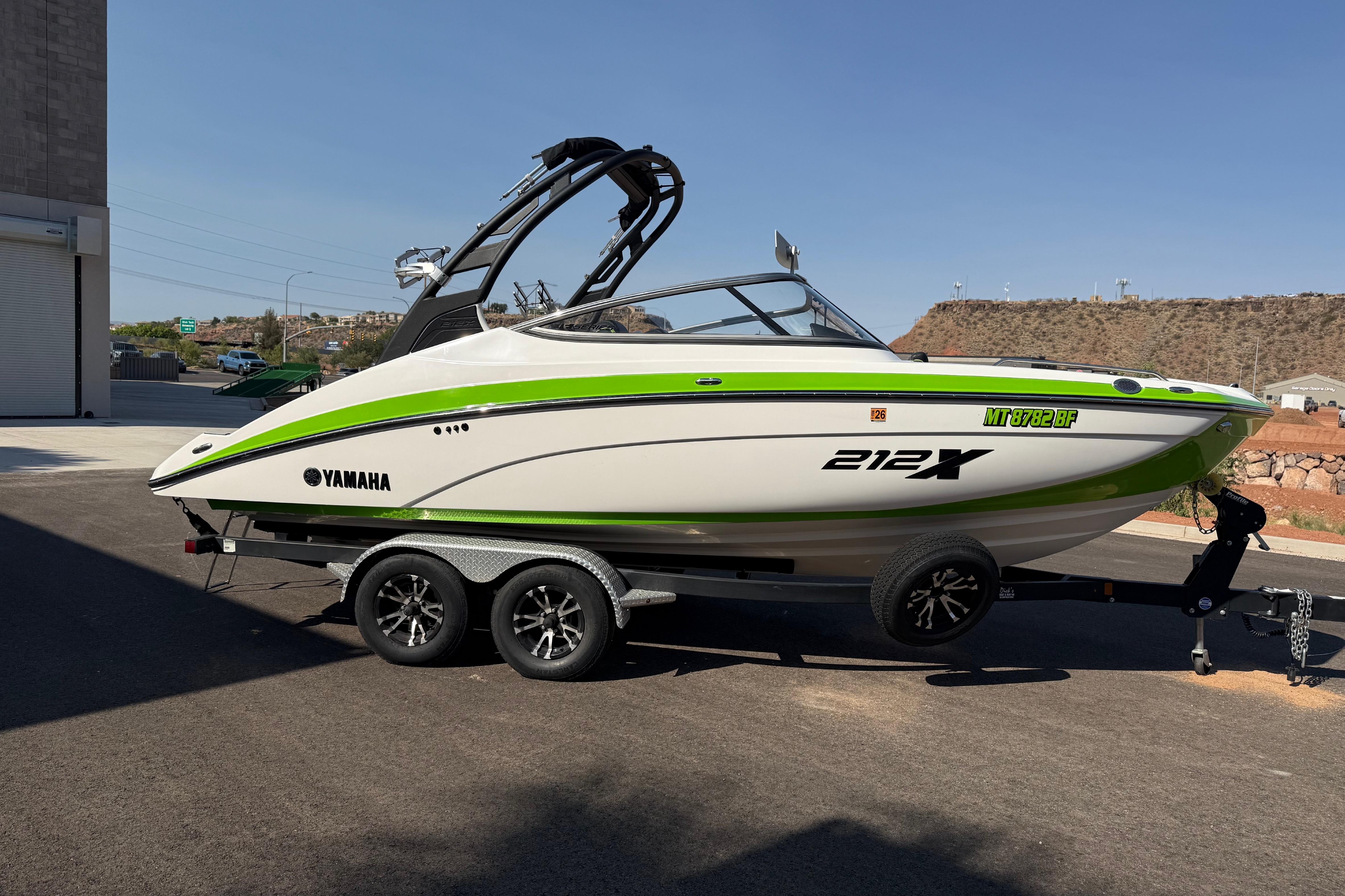 2022 Yamaha Boats 212XE in green and white on a trailer, parked outdoors.