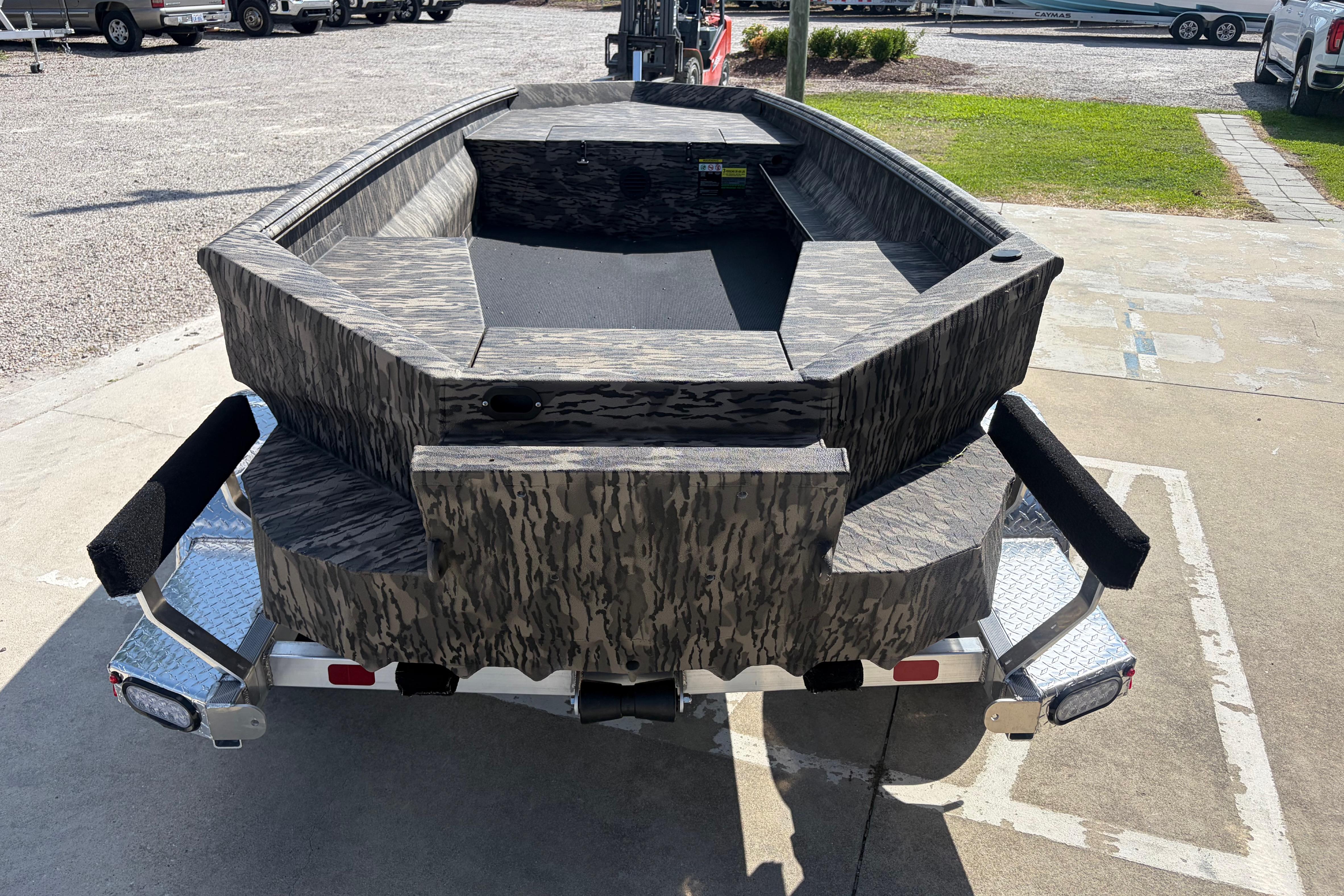 2026 Havoc 1653 VJST boat with camouflage design on a trailer, parked outdoors.
