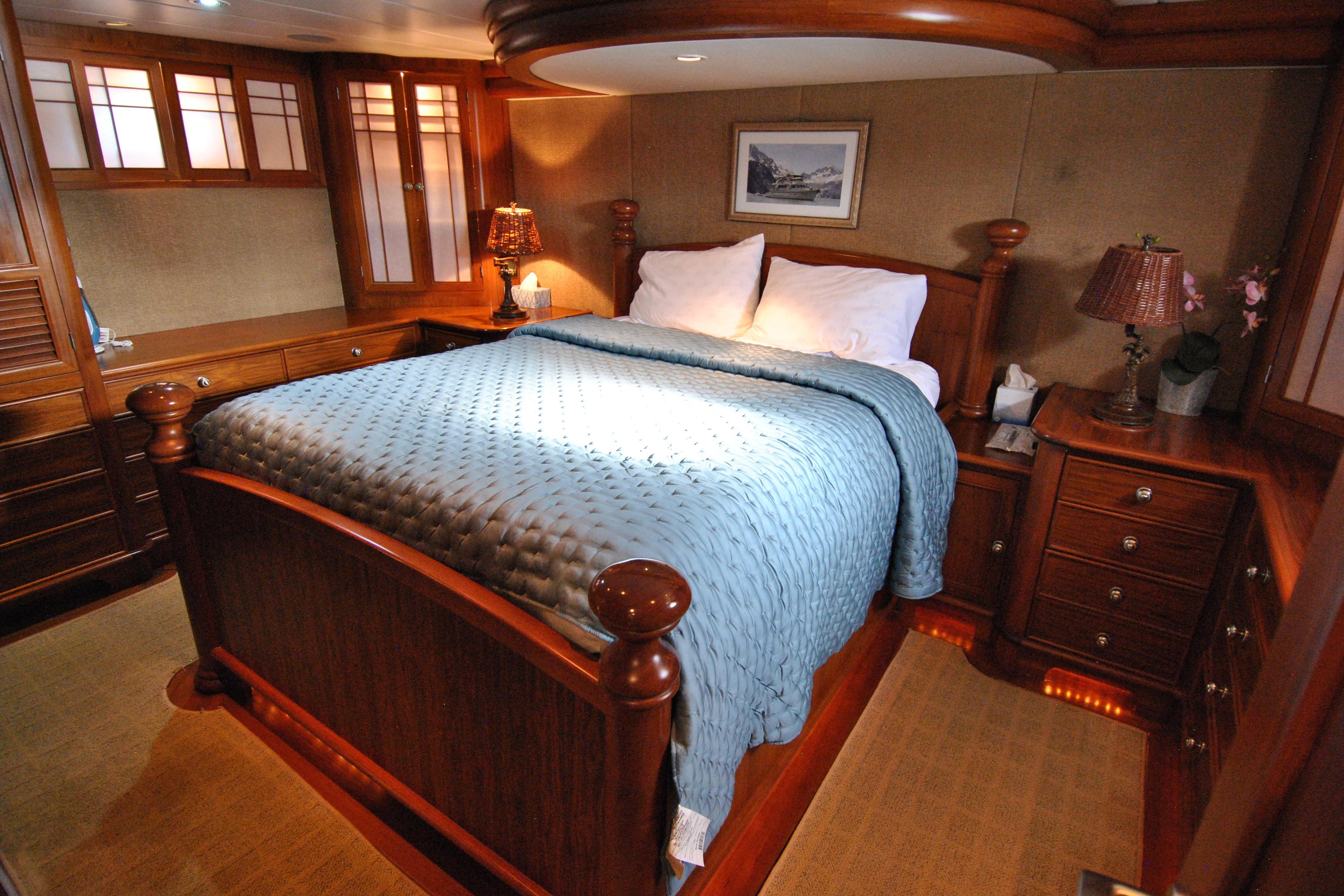 Luxurious 2002 Grand Alaskan Cockpit Motor Yacht bedroom with elegant wood furnishings.