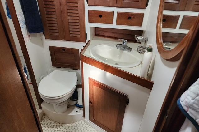 1984 Bristol 45.5 Center Cockpit bathroom with wooden cabinets and white fixtures.