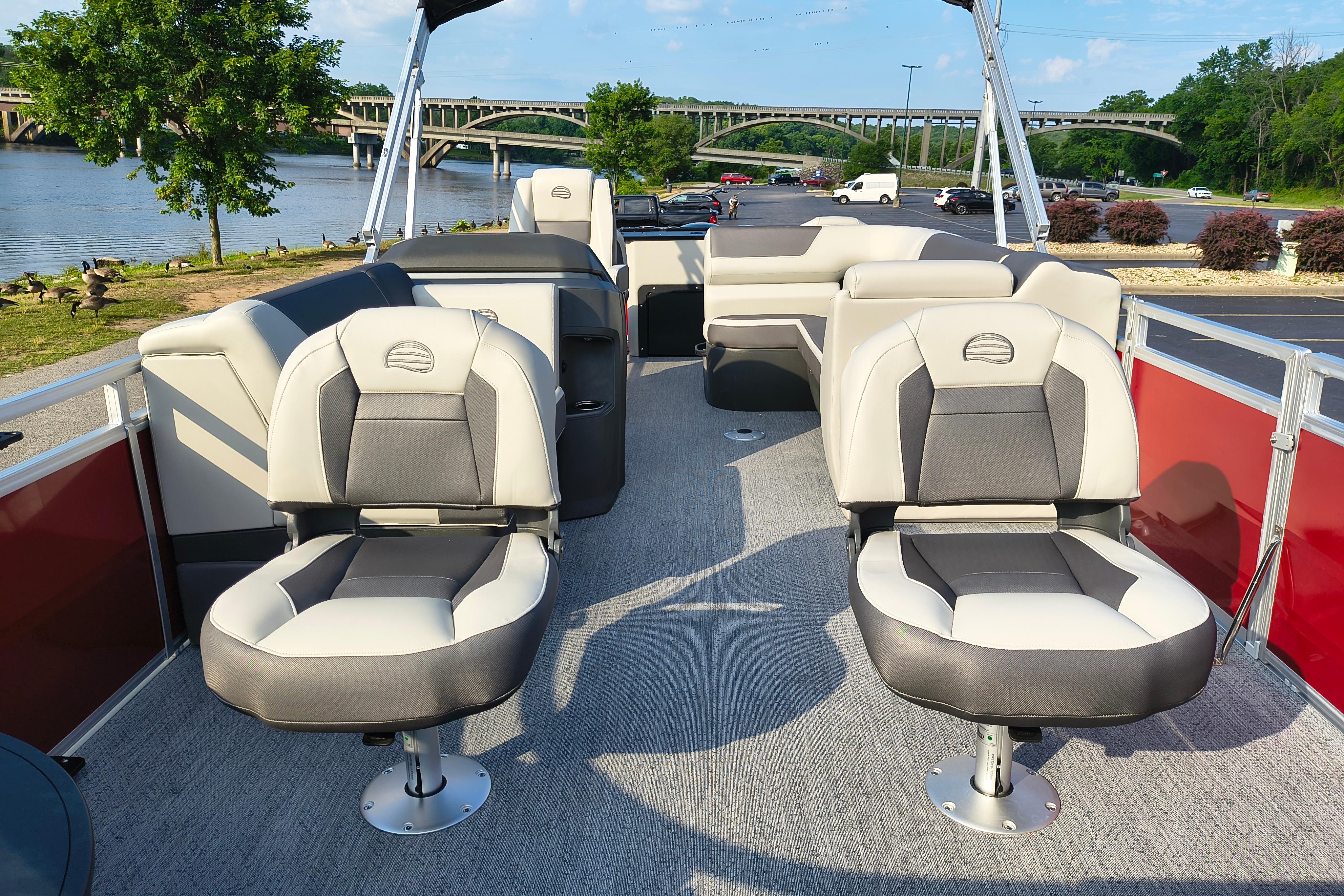 2026 Sun Tracker Fishin' Barge 22 DLX pontoon boat interior with comfortable seating by a scenic river.