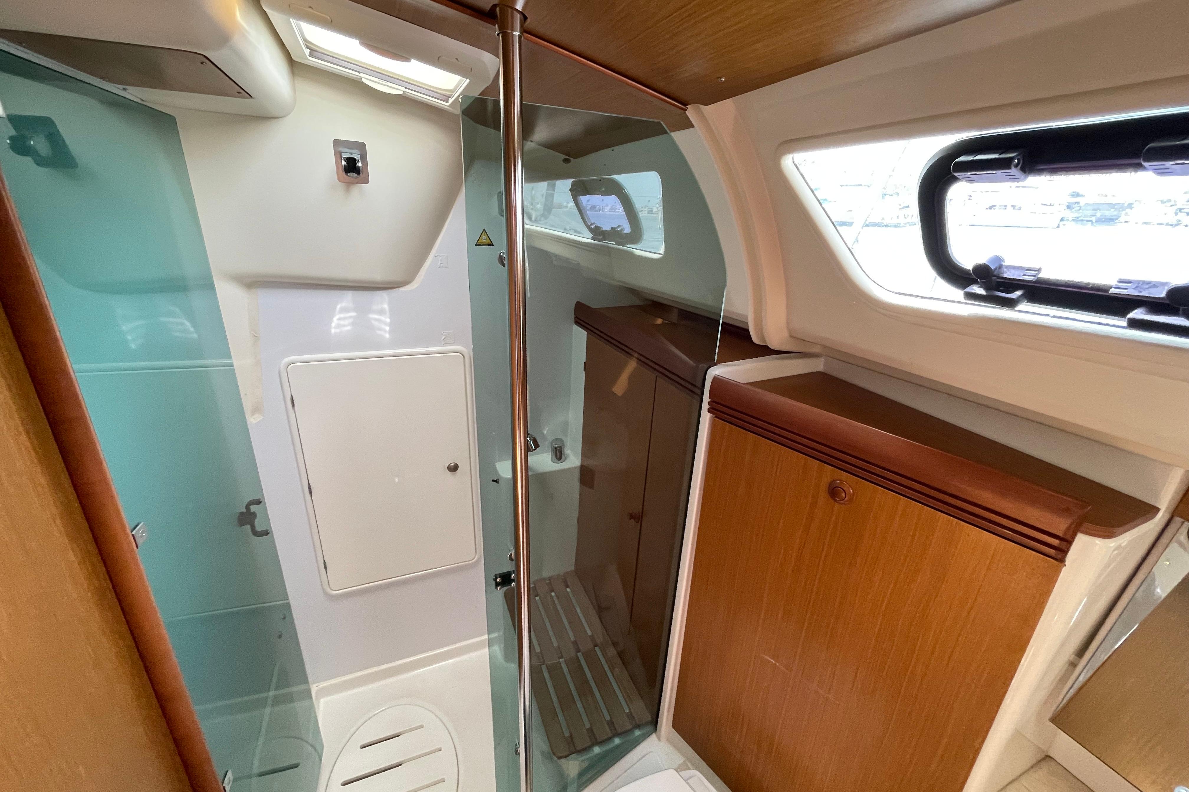 Interior of 2007 Jeanneau Sun Odyssey 39 DS yacht bathroom with shower and wooden cabinetry.