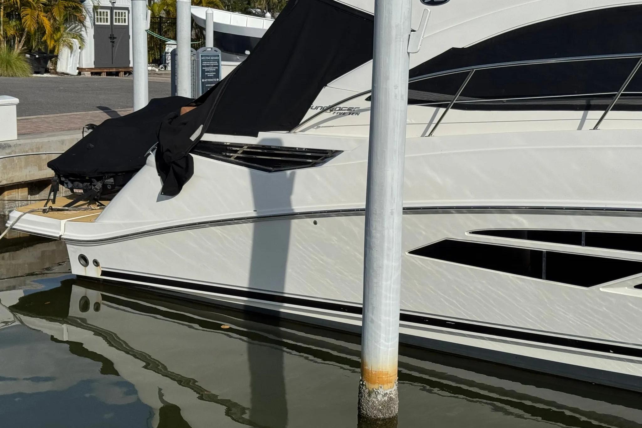 2016 Sea Ray Sundancer 510 yacht docked, partially covered, reflecting on calm water.