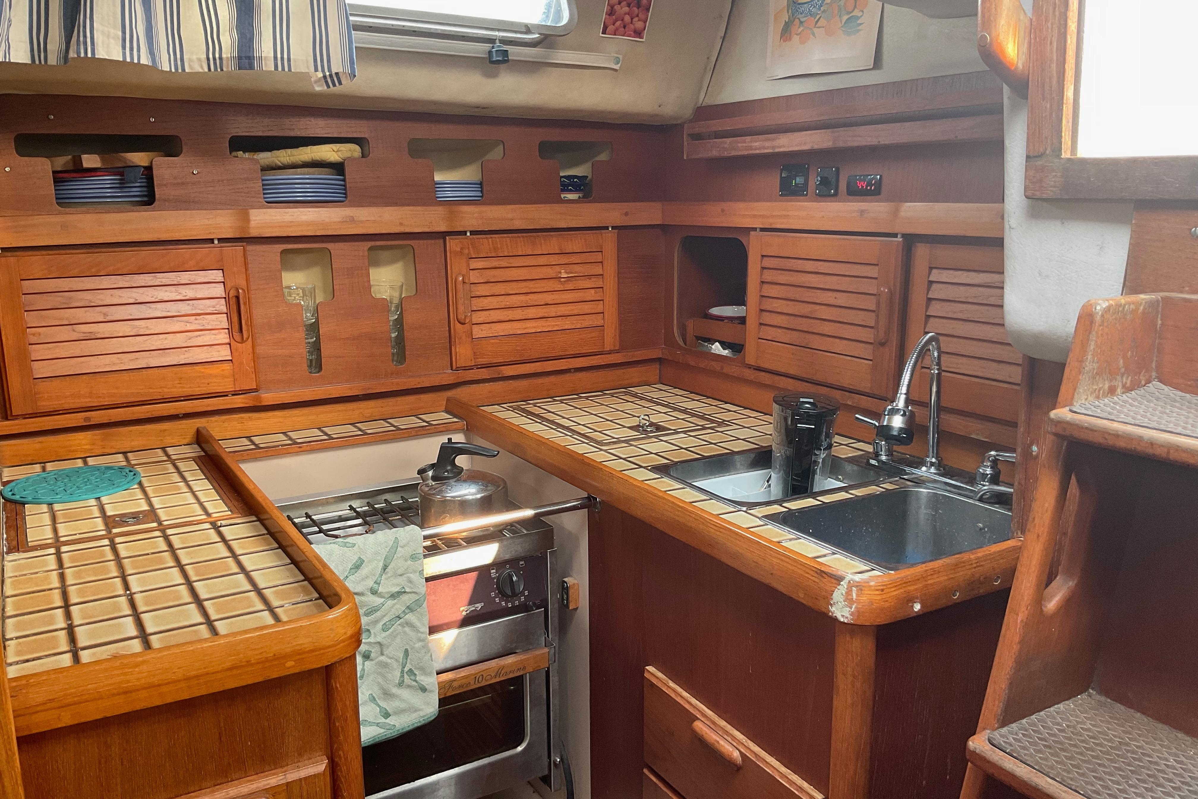 Interior of 1988 Westerly Corsair 36 sailboat kitchen with wooden cabinets and tiled countertops.