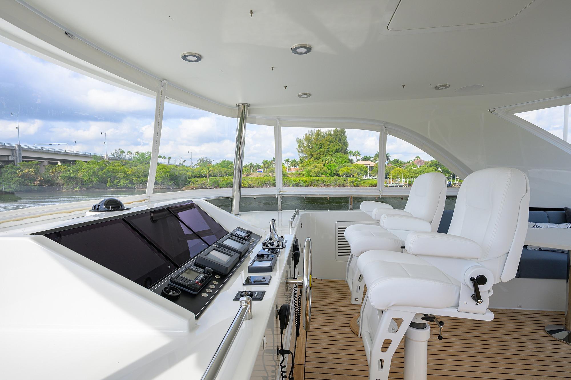 Pilothouse interior of 2016 Ocean Alexander 72, featuring modern navigation equipment and white captain chairs.