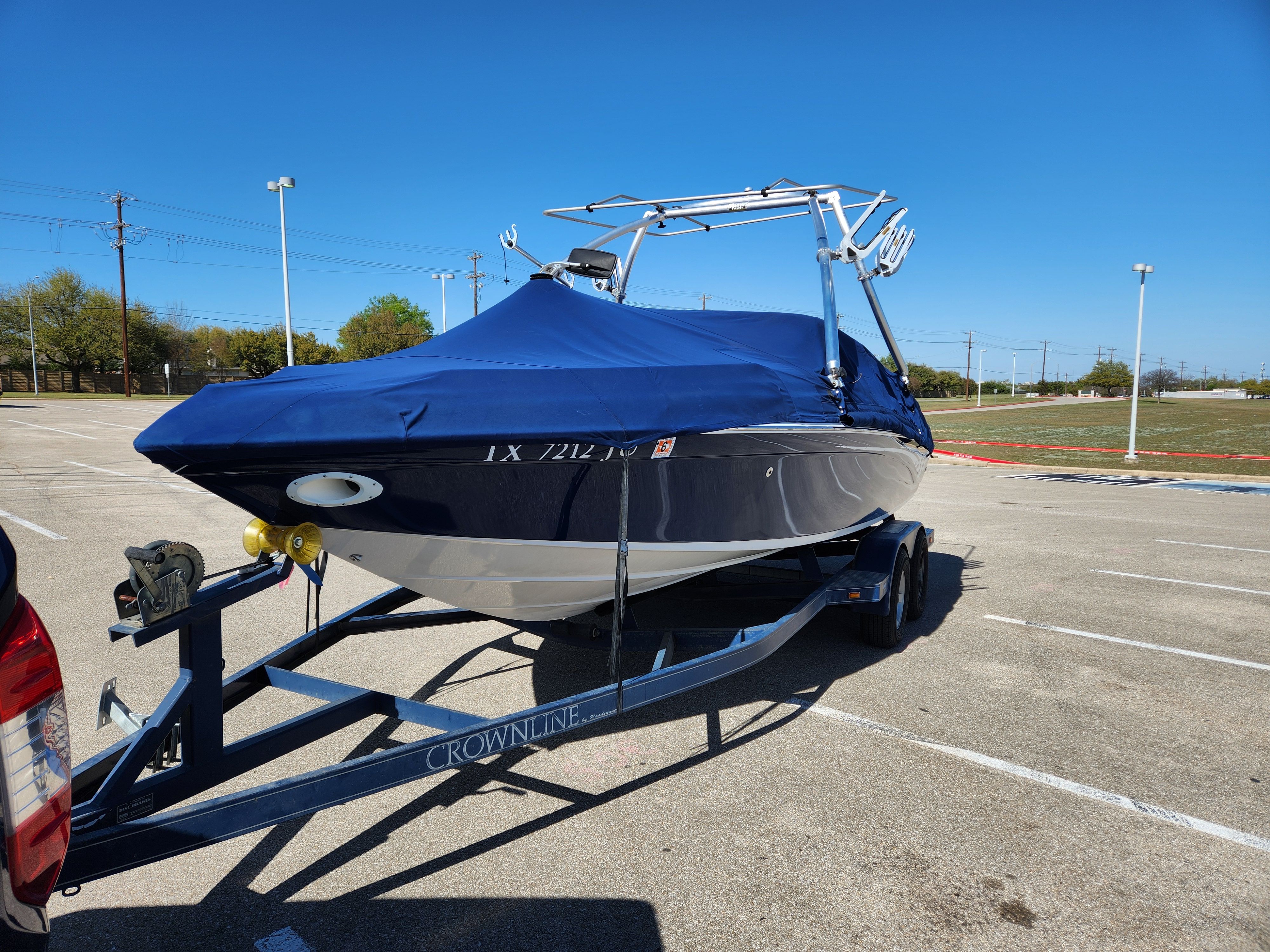 2003 Crownline 225 BR boat on trailer, blue cover, sunny parking lot.