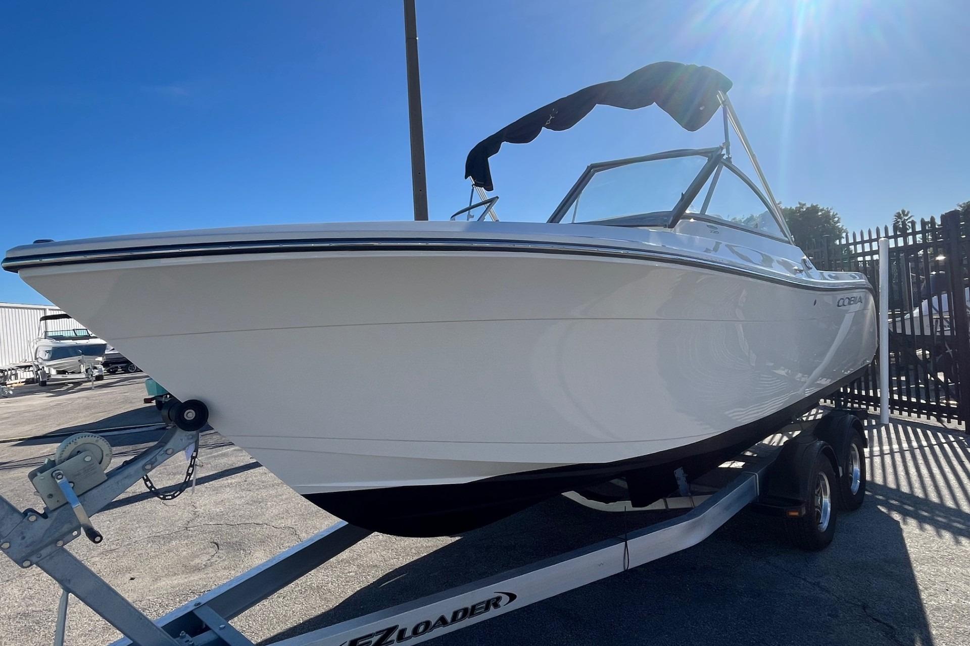 2023 Cobia 220 Dual Console boat on trailer under clear blue sky.