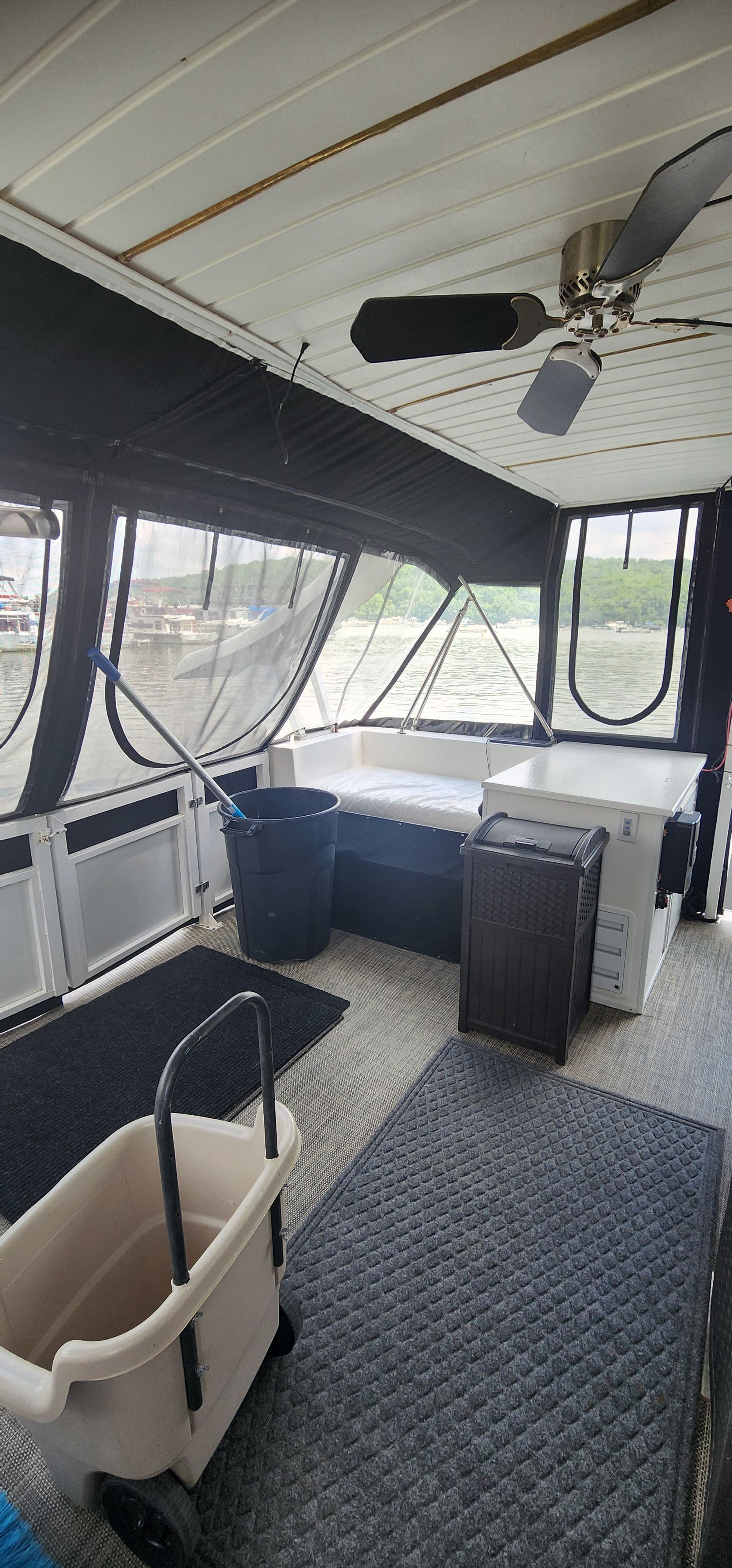 The image shows a boat interior with a ceiling fan and large windows.