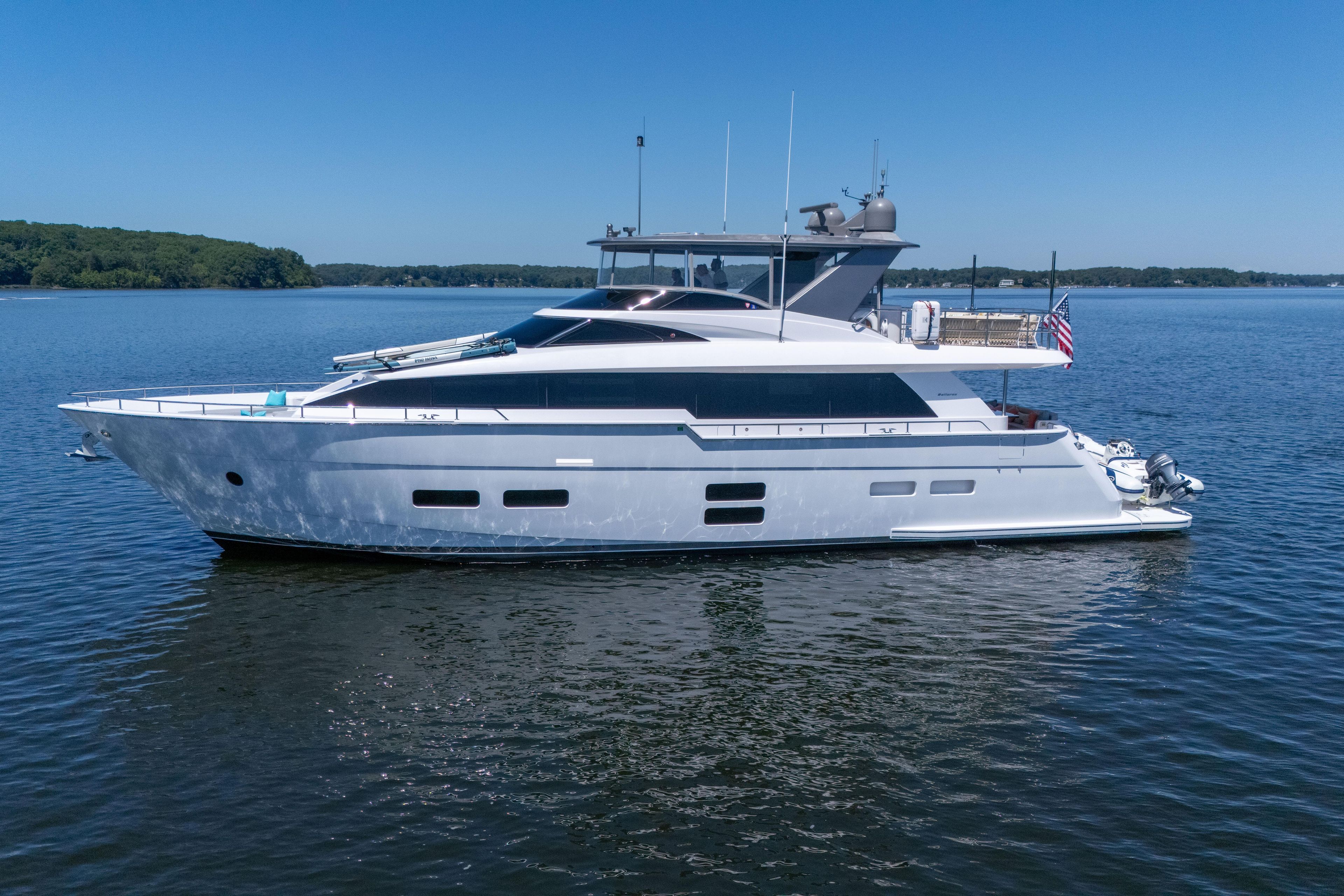 2021 Hatteras M75 Panacera yacht cruising on a serene lake under clear blue skies.