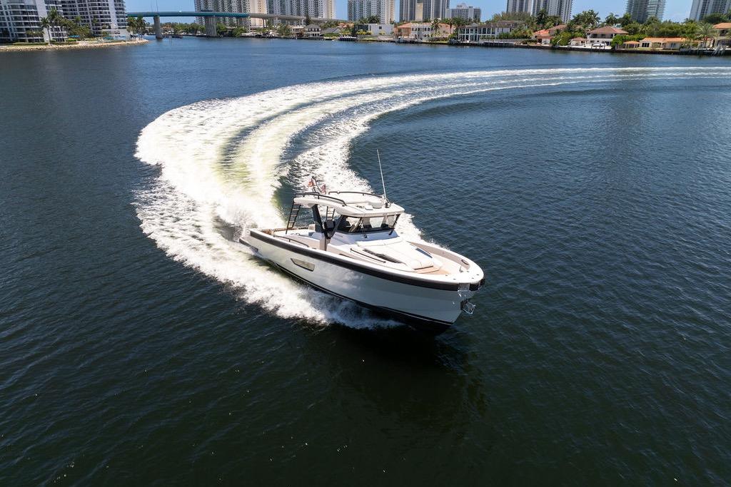 2021 Bluegame BG 42 yacht cruising on a scenic waterway with city skyline.