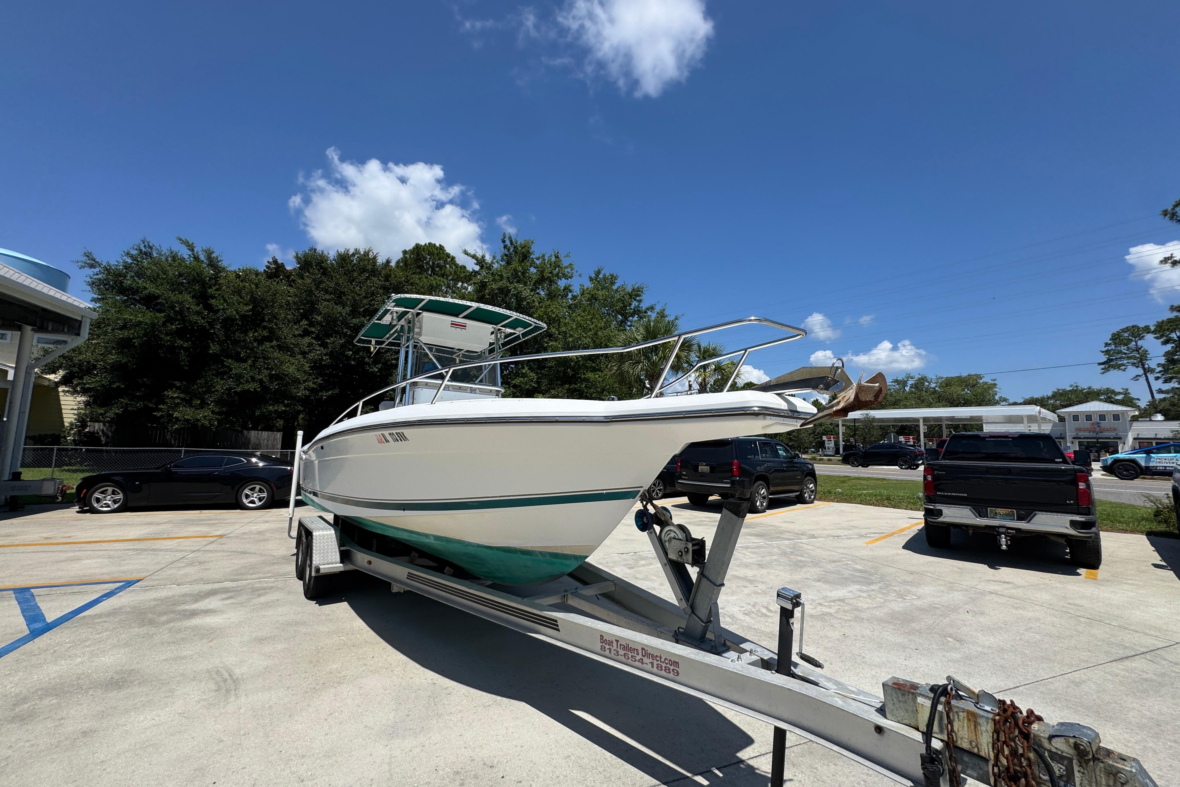 2000 Stamas 250 Tarpon boat on trailer in parking lot under clear blue sky.