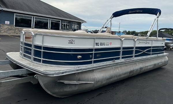 A 2018 South Bay S224CR pontoon boat on a trailer in front of a building.